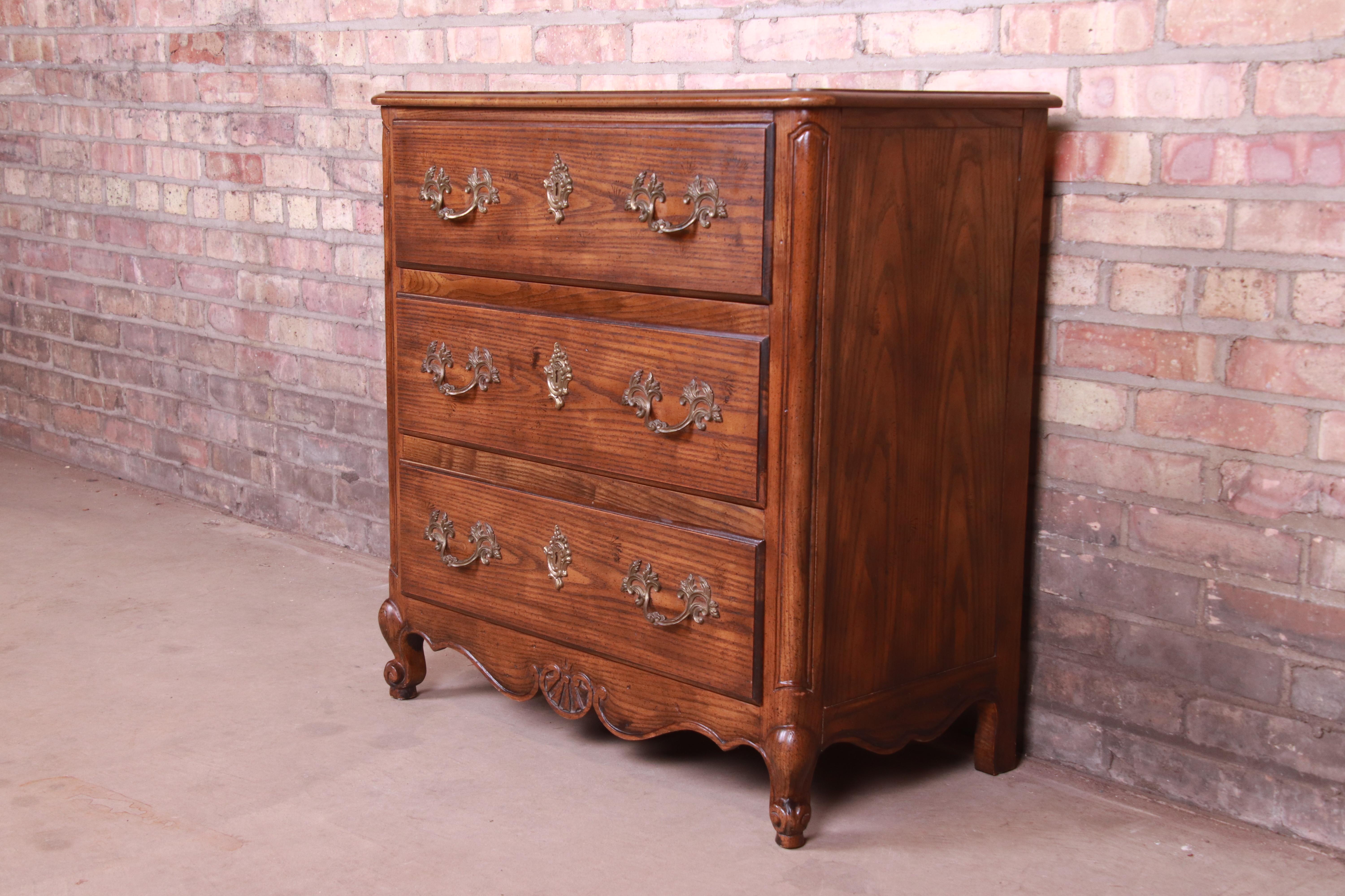 An exceptional French Provincial Louis XV style chest of drawers or commode

By Baker Furniture

USA, circa 1980s

Carved oak, with burl wood top and original brass hardware.

Measures: 29.5