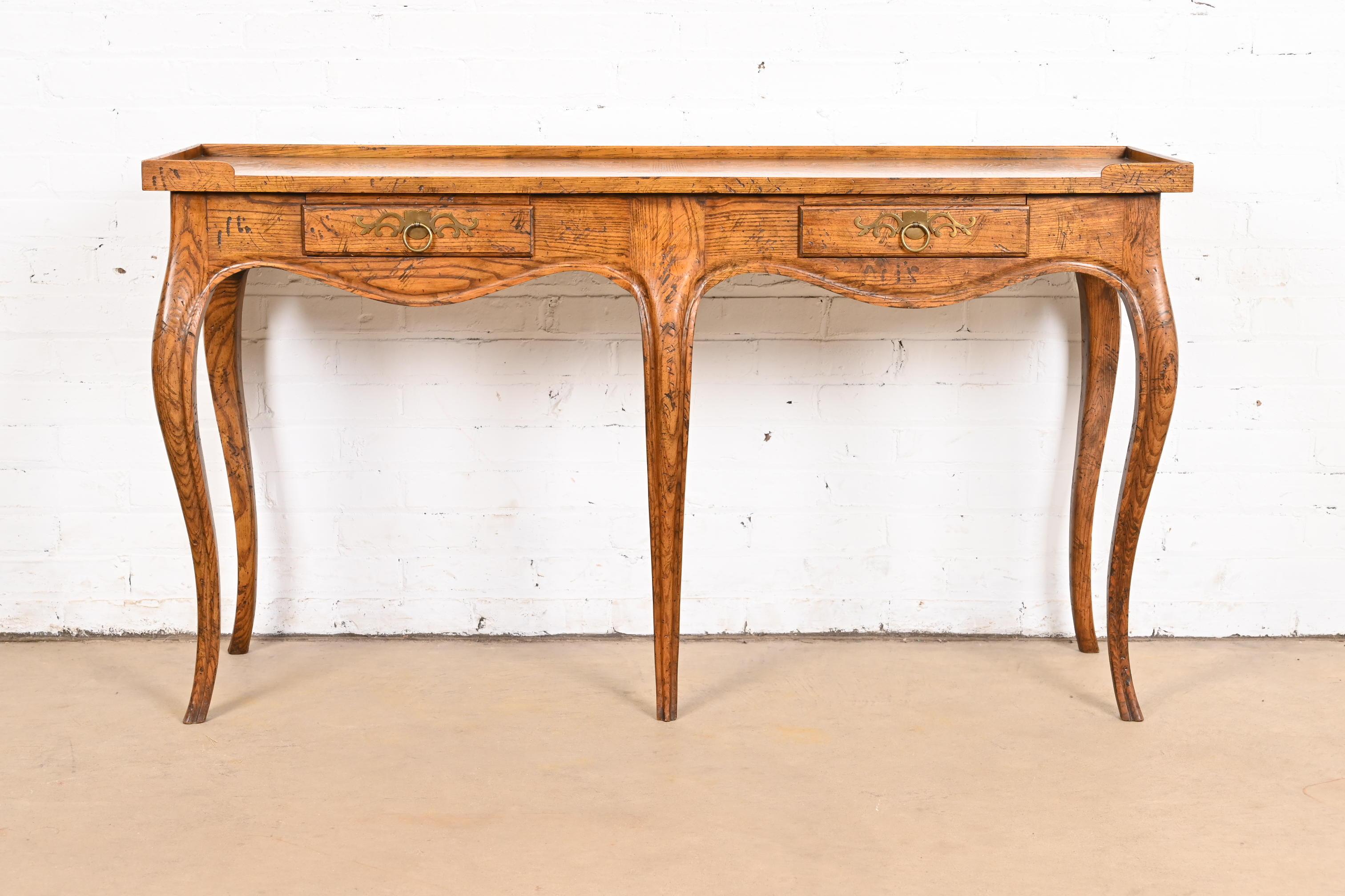 A gorgeous French Country or French Provincial Louis XV style console table or server

By Baker Furniture 

USA, Circa 1960s

Carved oak, with beautiful book-matched burl wood top, and original brass hardware.

Measures: 54