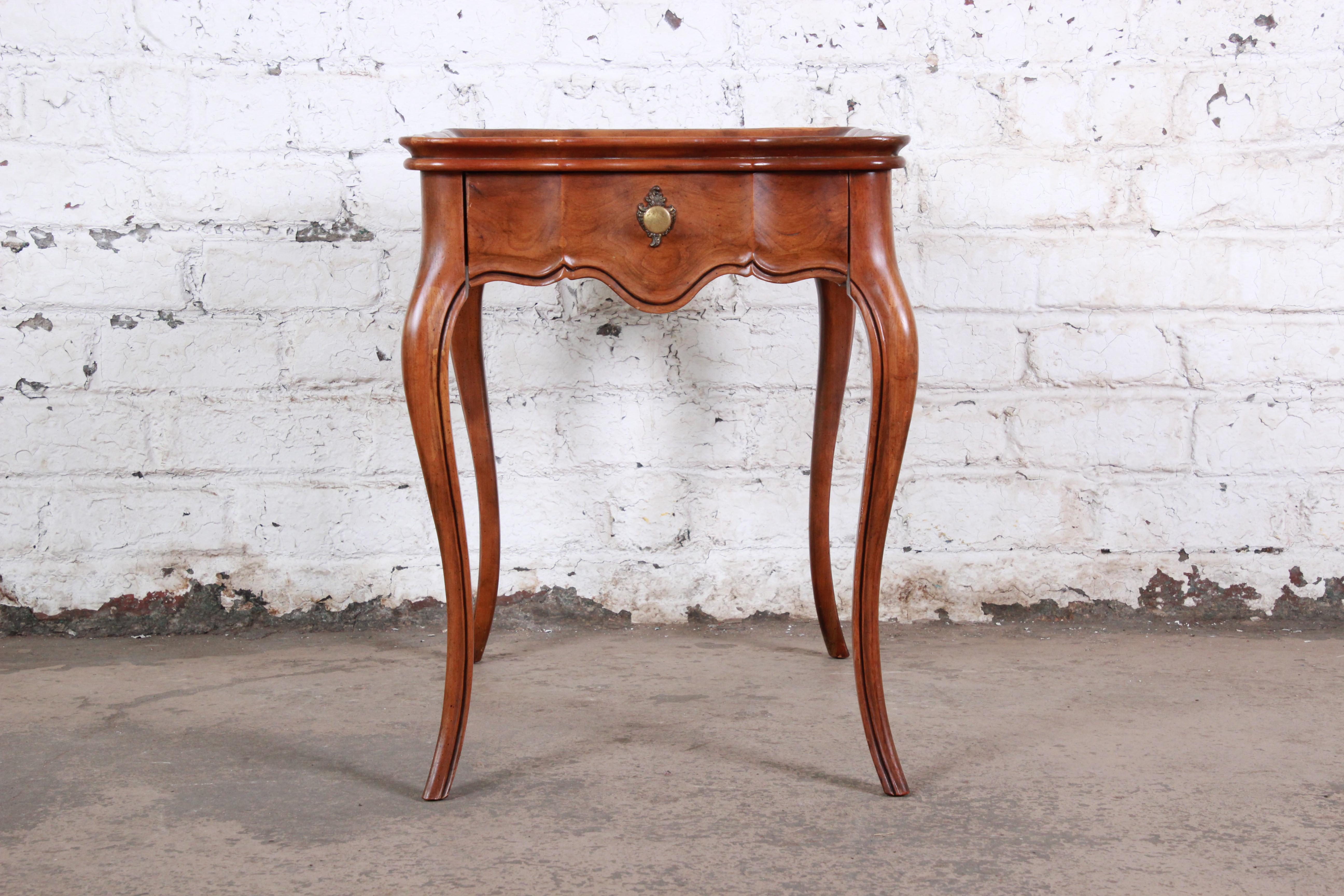 An excellent baker furniture French provincial burled walnut side table or end table. The table has Classic French styled legs with a French provincial design with its stunning burled walnut top. The table offers one drawer for storage. The table is