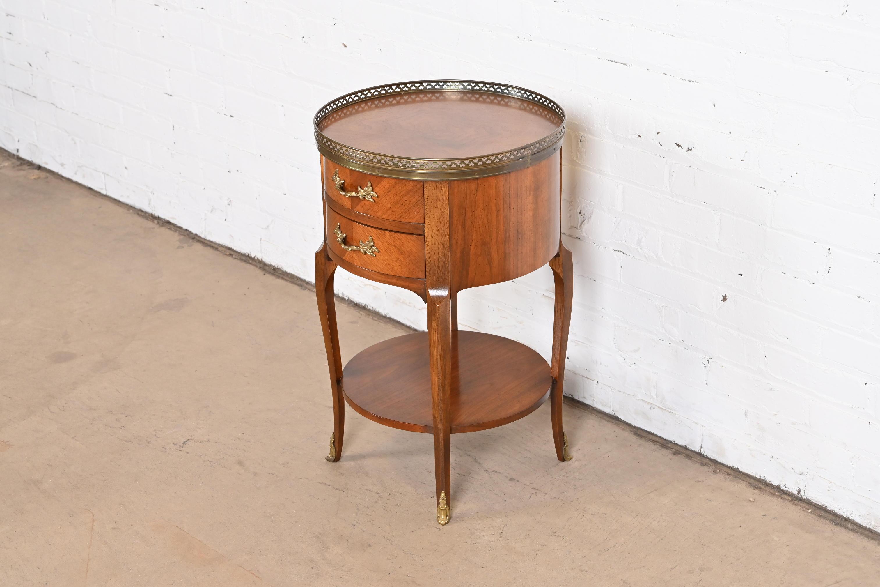 A gorgeous French Provincial Louis XV style gueridon, nightstand, tea table, or occasional side table.

By Baker Furniture

USA, circa 1960s

Stunning inlaid and carved walnut, with brass gallery and hardware.

Measures: 16