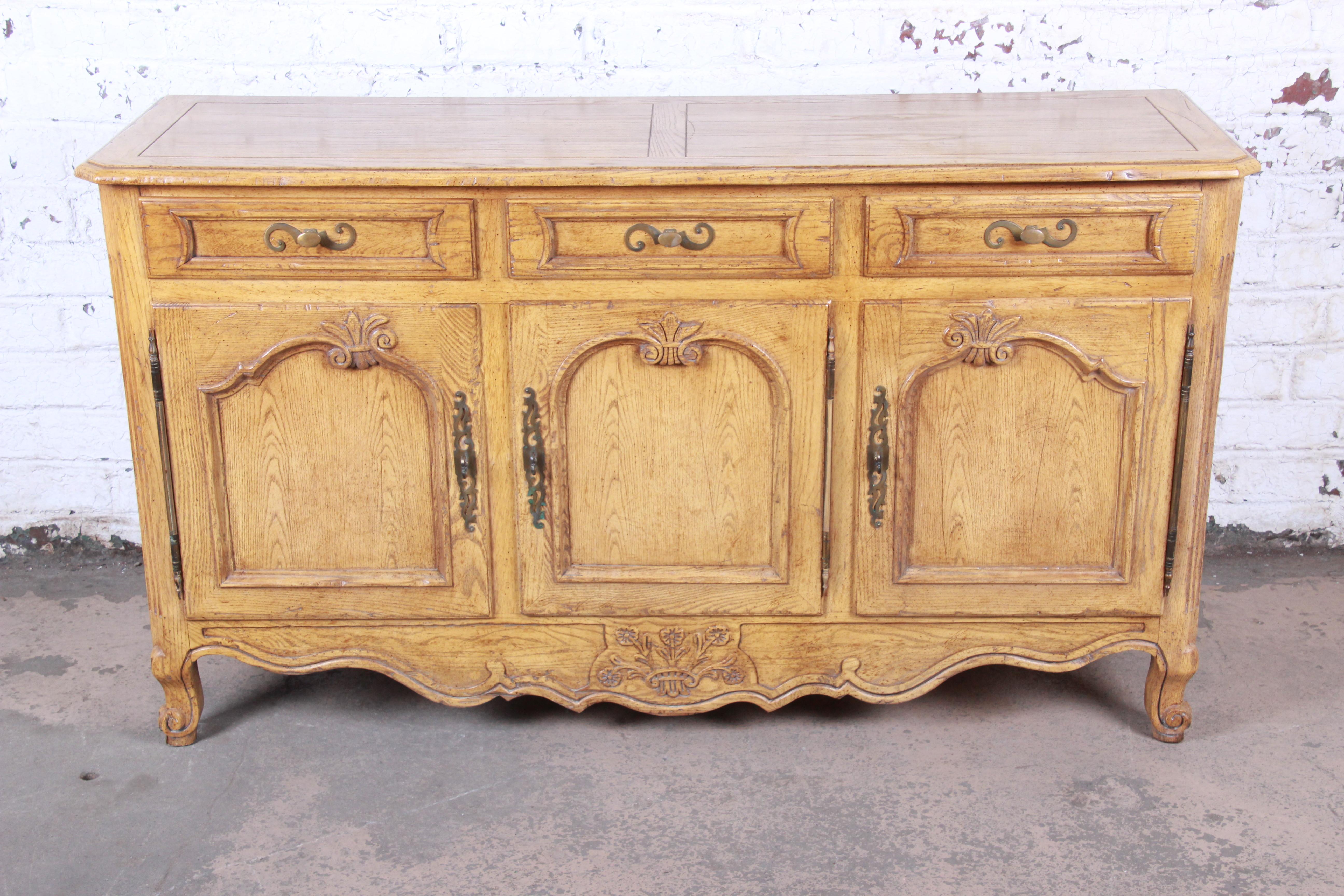 A gorgeous French Country Louis XV style white oak sideboard buffet or credenza

By Baker Furniture

USA, circa 1960s

Oak and original brass hardware

Measures: 62