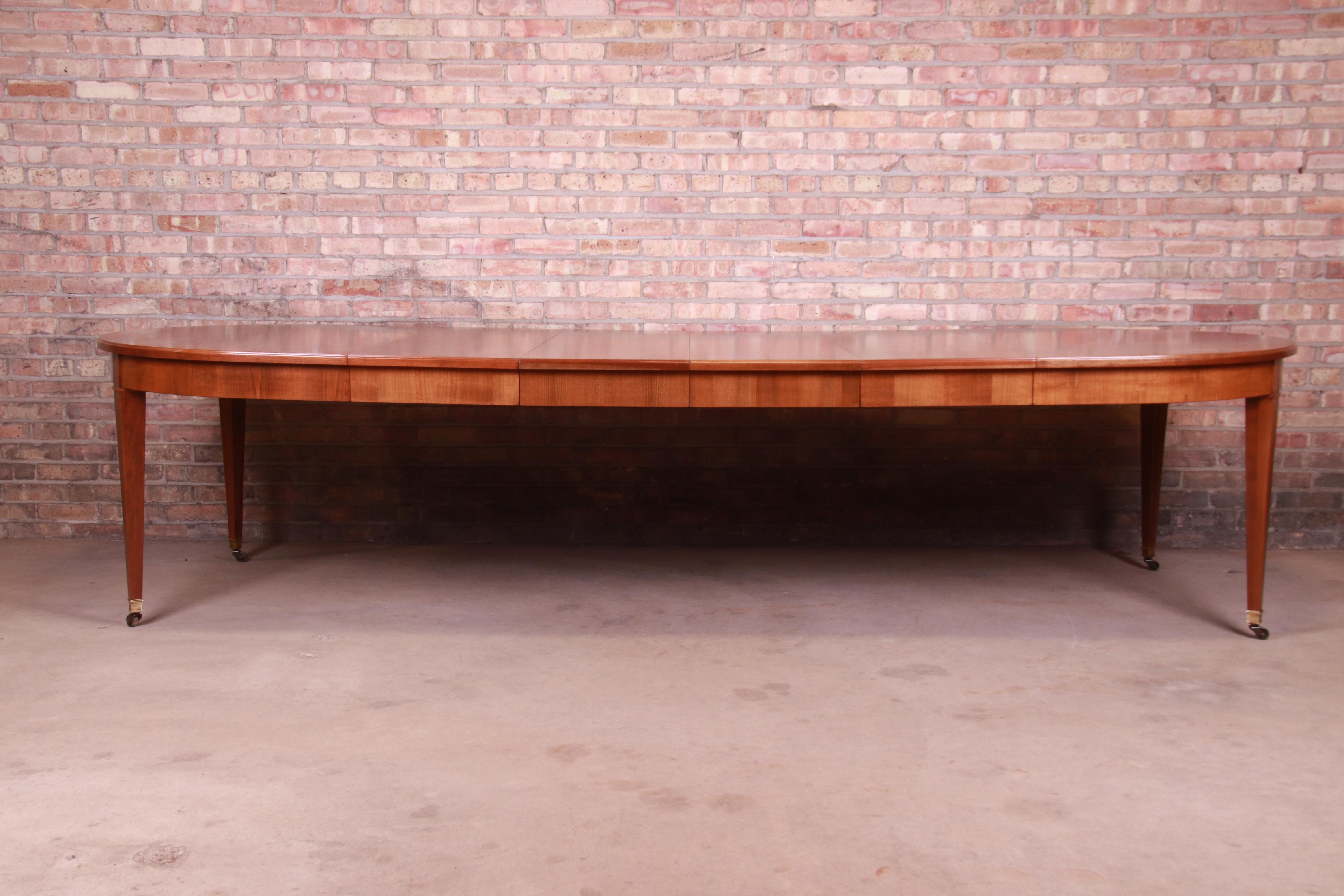 An exceptional midcentury French Regency style extension dining table

By Baker Furniture

USA, circa 1950s

Book-matched cherrywood, with brass sabots and original casters.

Measures: 63