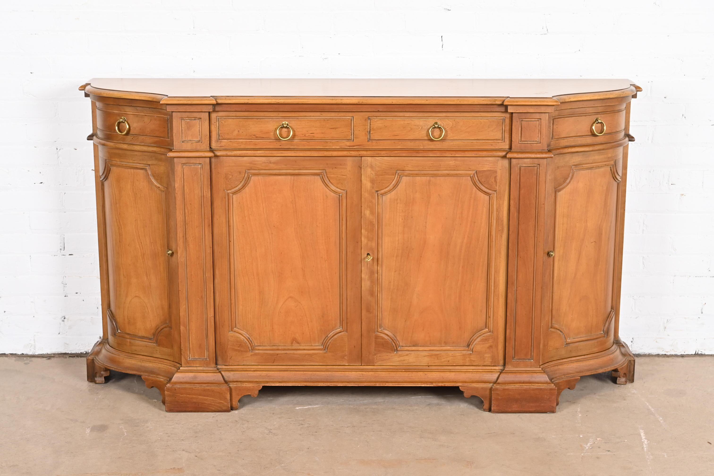 A gorgeous French Regency style sideboard, credenza, or bar cabinet

By Baker Furniture

USA, Circa 1960s

Carved cherry wood, with original brass hardware. Cabinet locks, and key is included.

Measures: 64