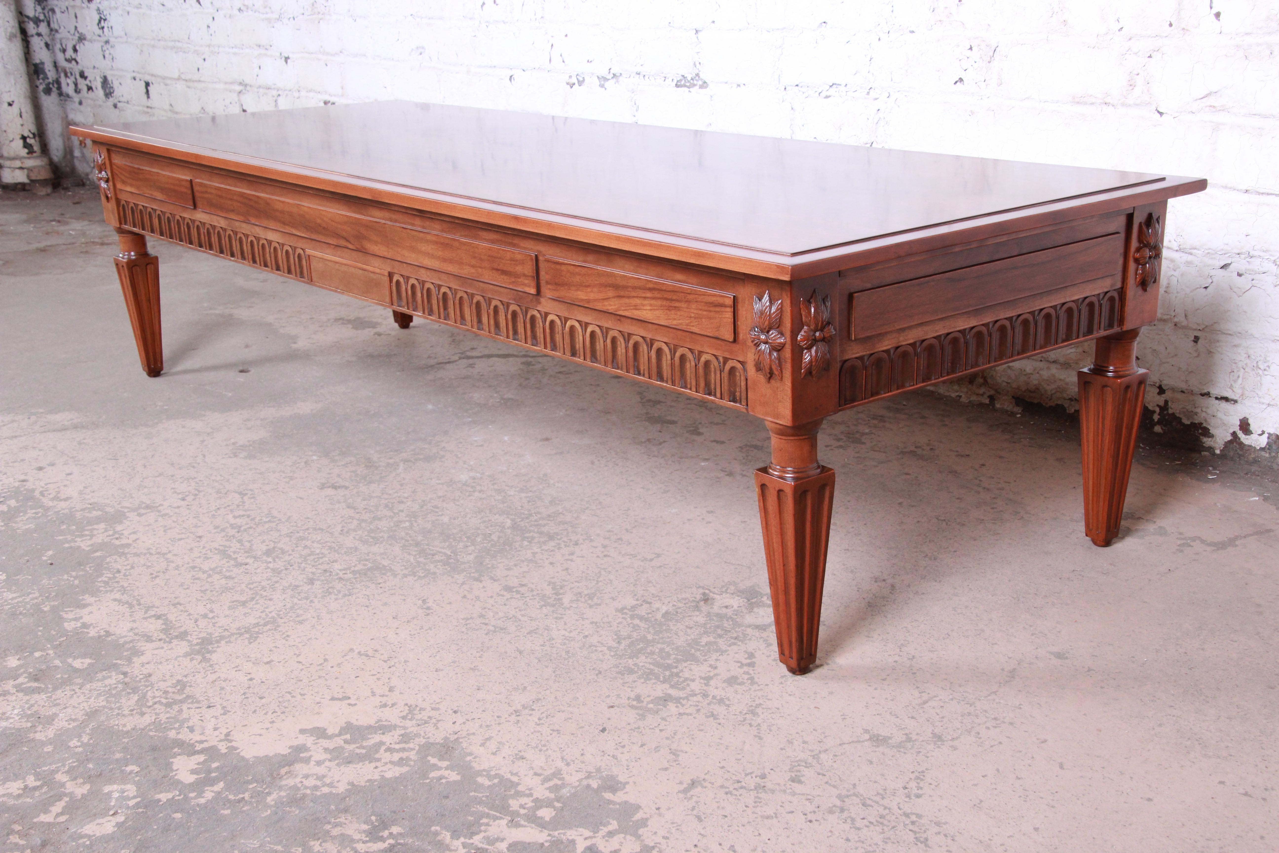 An exceptional French Regency Louis XVI style coffee table by Baker Furniture. The table features stunning burled walnut wood grain and beautiful carved wood details. Made with the highest quality craftsmanship as expected from Baker. The original