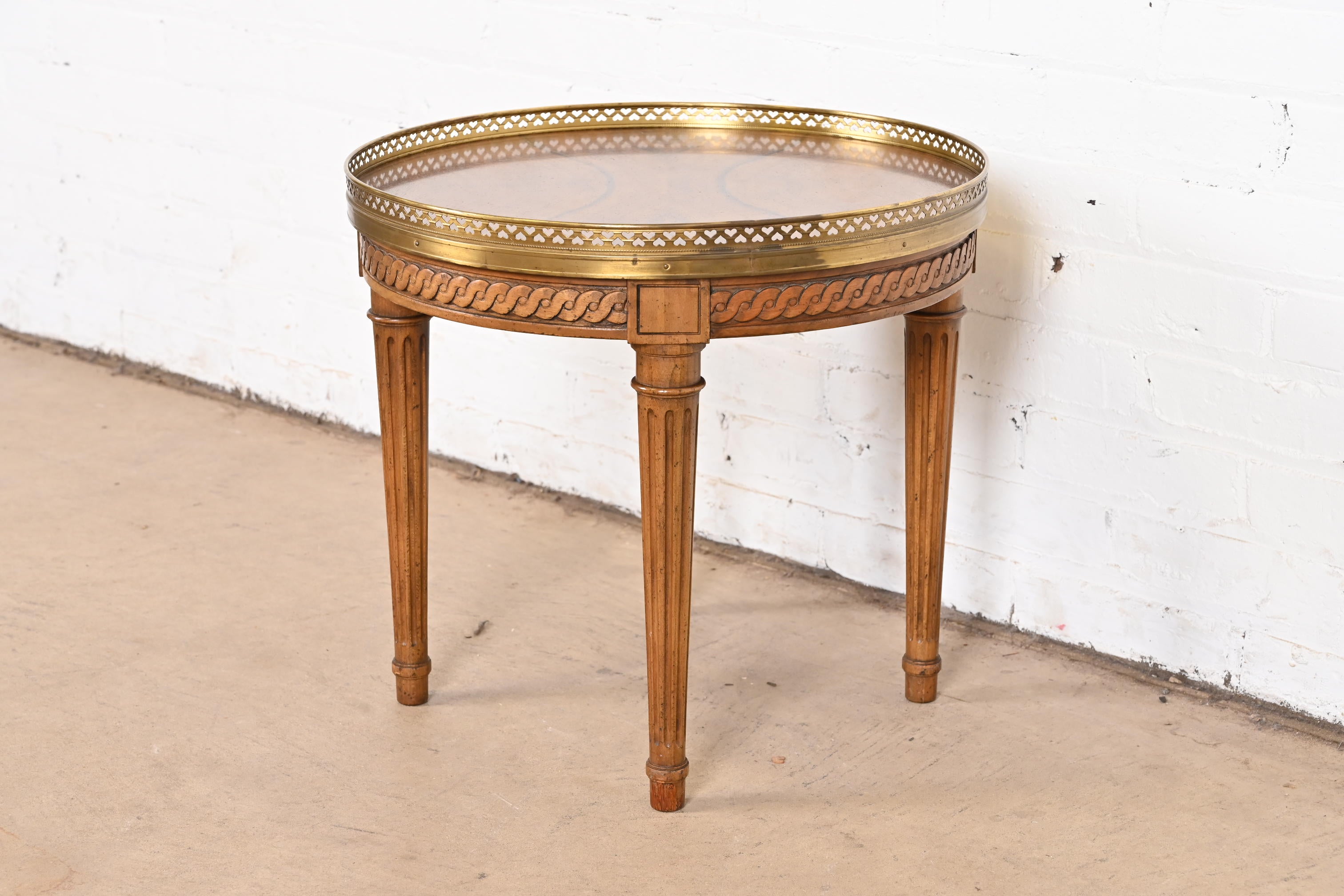 A gorgeous French Regency Louis XVI style tea table or occasional side table

By Baker Furniture

USA, Circa 1960s

Book-matched burled walnut top, with carved walnut legs, and brass gallery.

Measures: 18.5