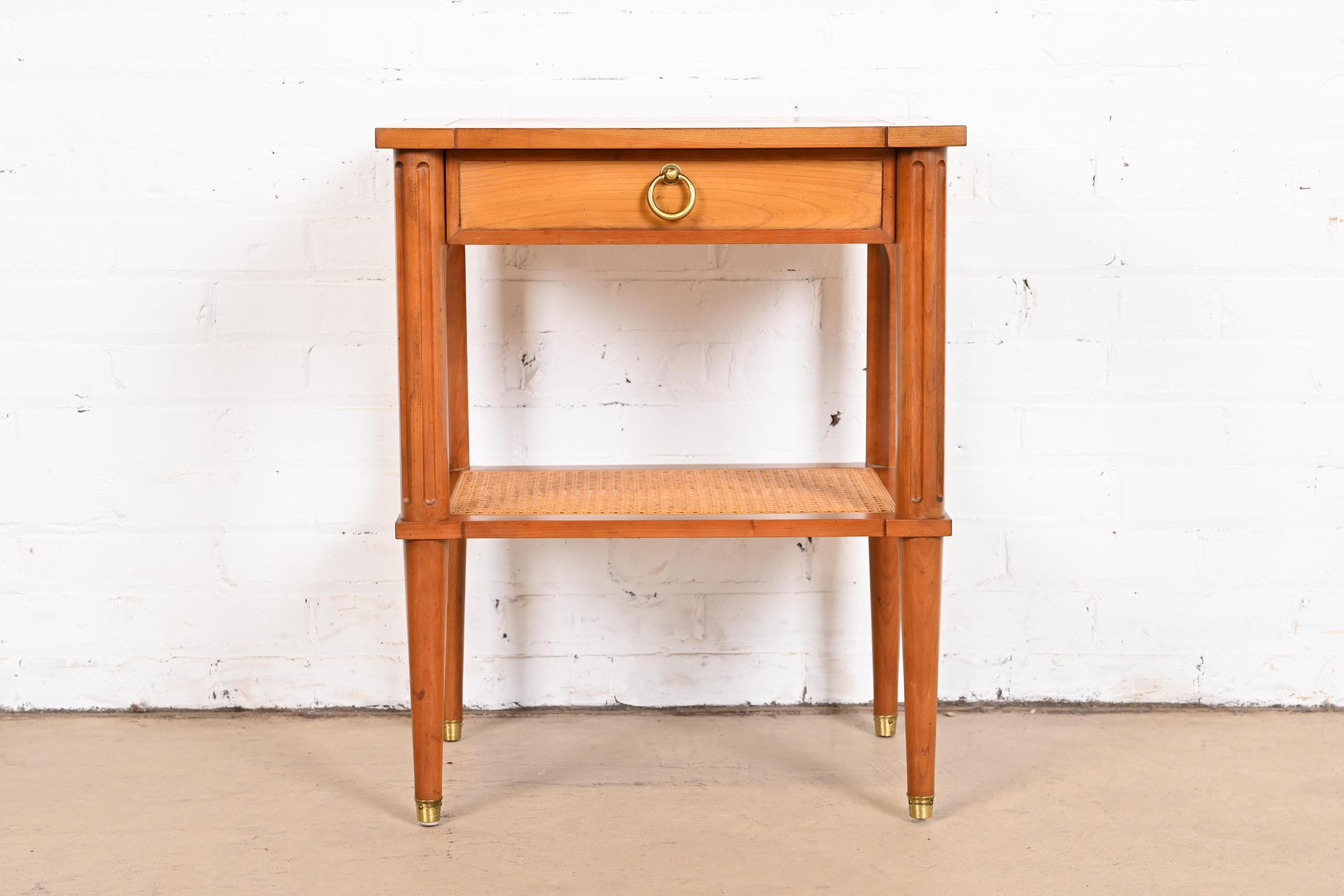 A gorgeous French Regency Louis XVI style two-tier nightstand or tea table

By Baker Furniture

USA, circa 1960s

Carved cherry wood, with caned lower shelf and brass hardware.

Measures: 20.5