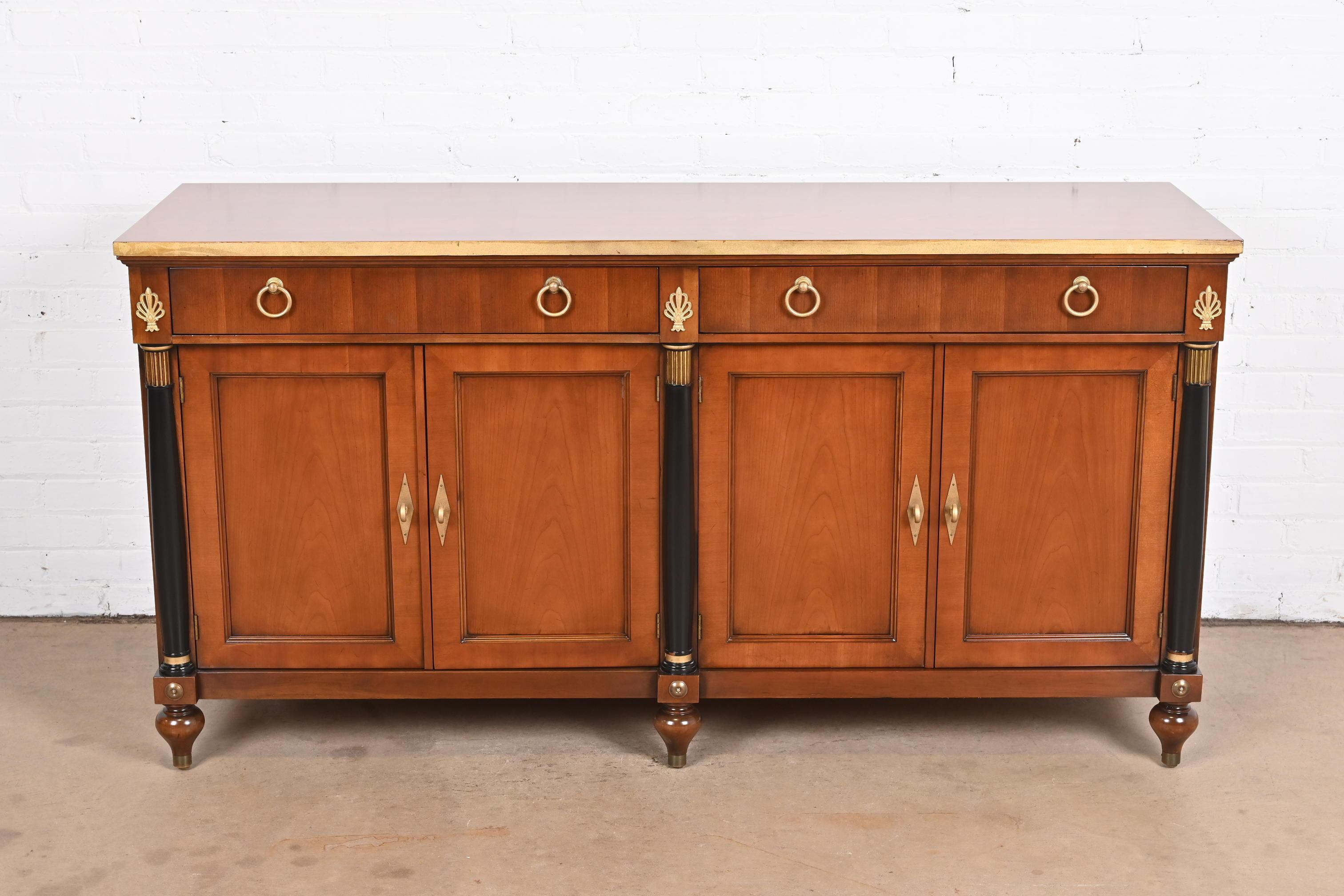 A gorgeous French Regency Louis XVI or Empire style sideboard, credenza, or bar cabinet

By Baker Furniture

USA, circa 1980s

Carved cherry wood, with ebonized columns, gilt trim, and original brass hardware.

Measures: 64