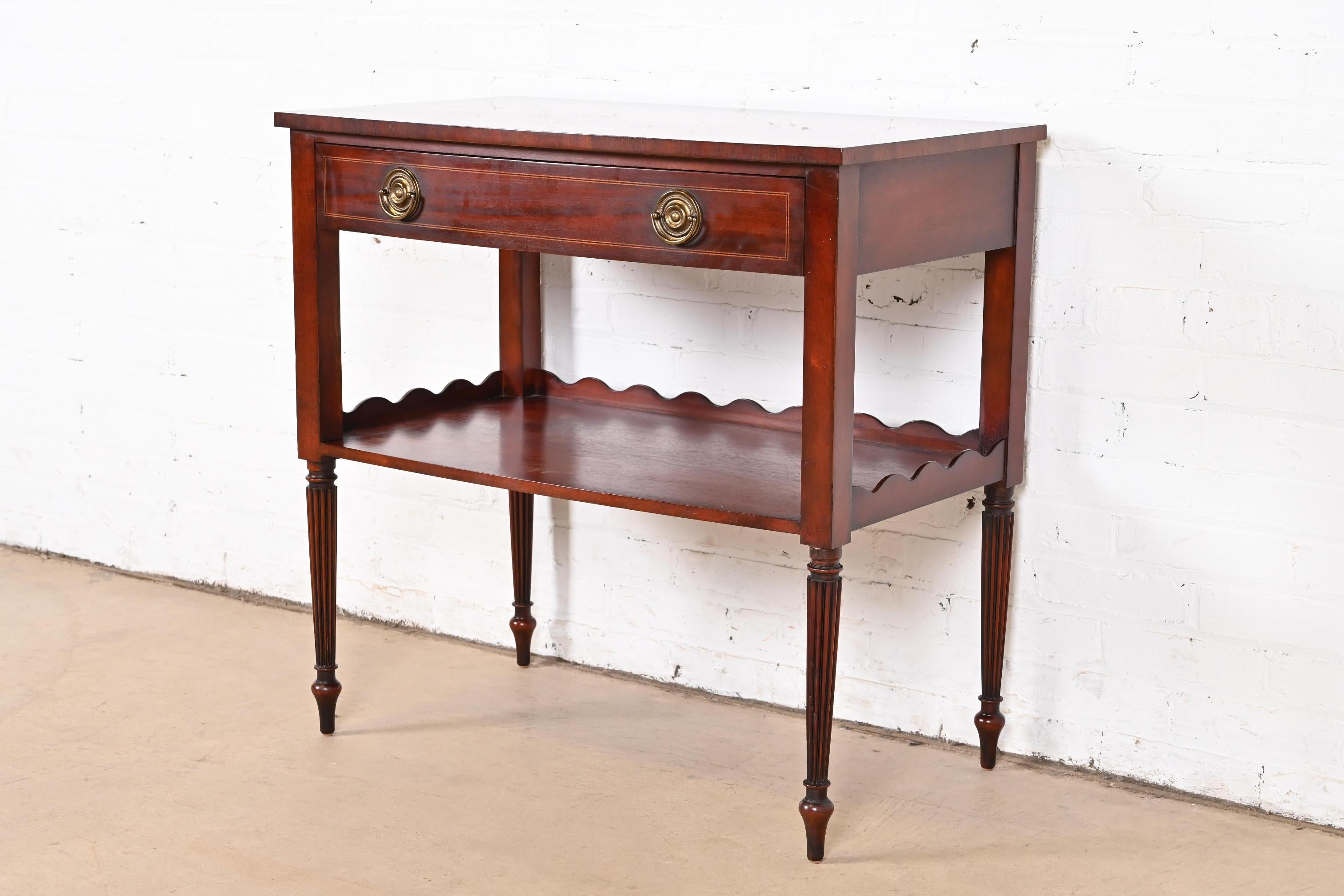 Exceptionnel serveur de buffet, table à thé ou table d'appoint à deux niveaux de style Régence française Louis XVI.

Par Baker Furniture

USA, Circa 1980

Acajou sculpté, avec incrustation de bois satiné et quincaillerie en laiton