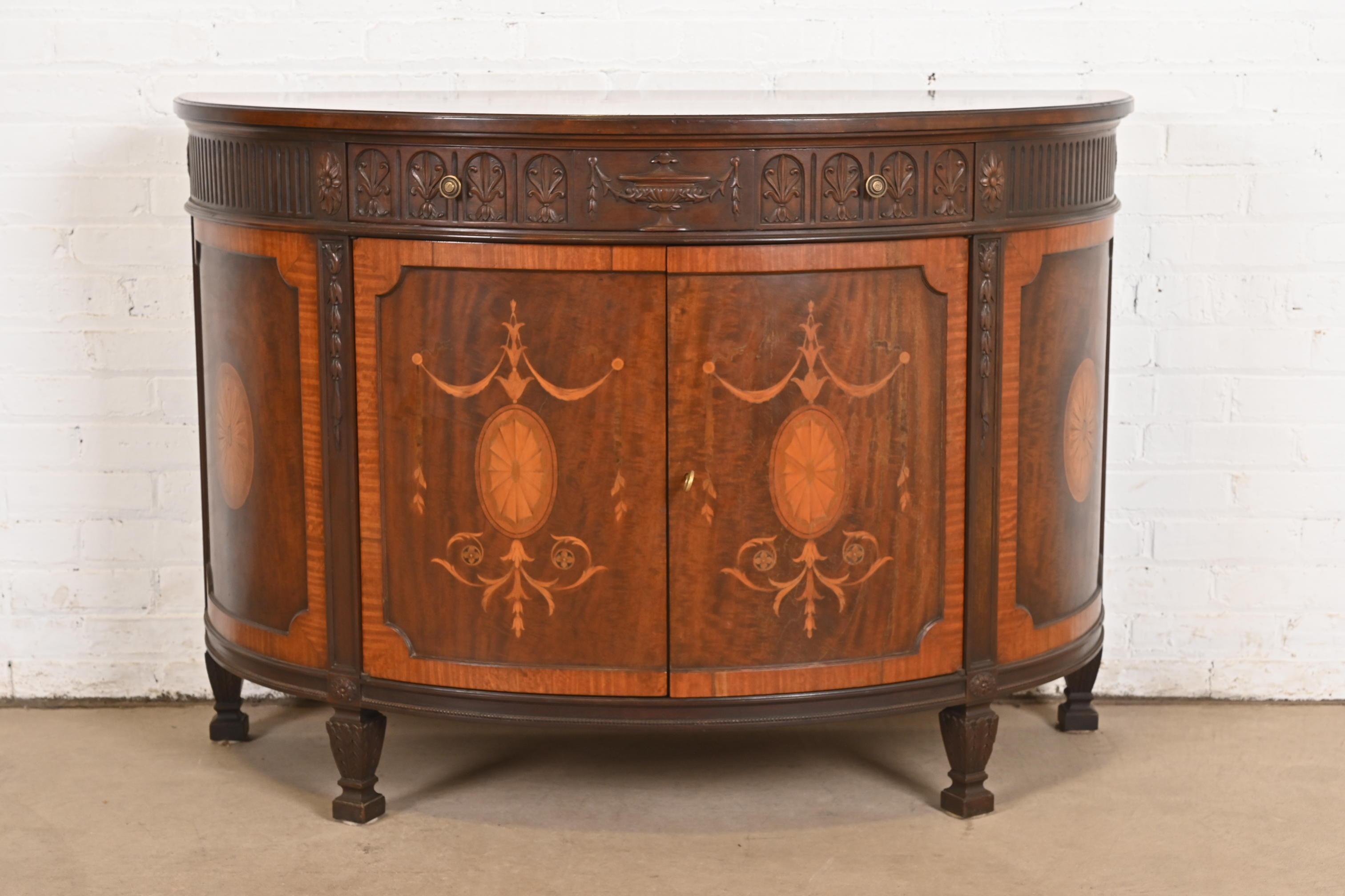 A gorgeous French Regency Louis XVI style demilune cabinet, console table, or bar cabinet

By Baker Furniture

USA, Circa 1960s

Beautiful carved mahogany, with inlaid satinwood marquetry, and original brass hardware. Cabinet locks, and key is
