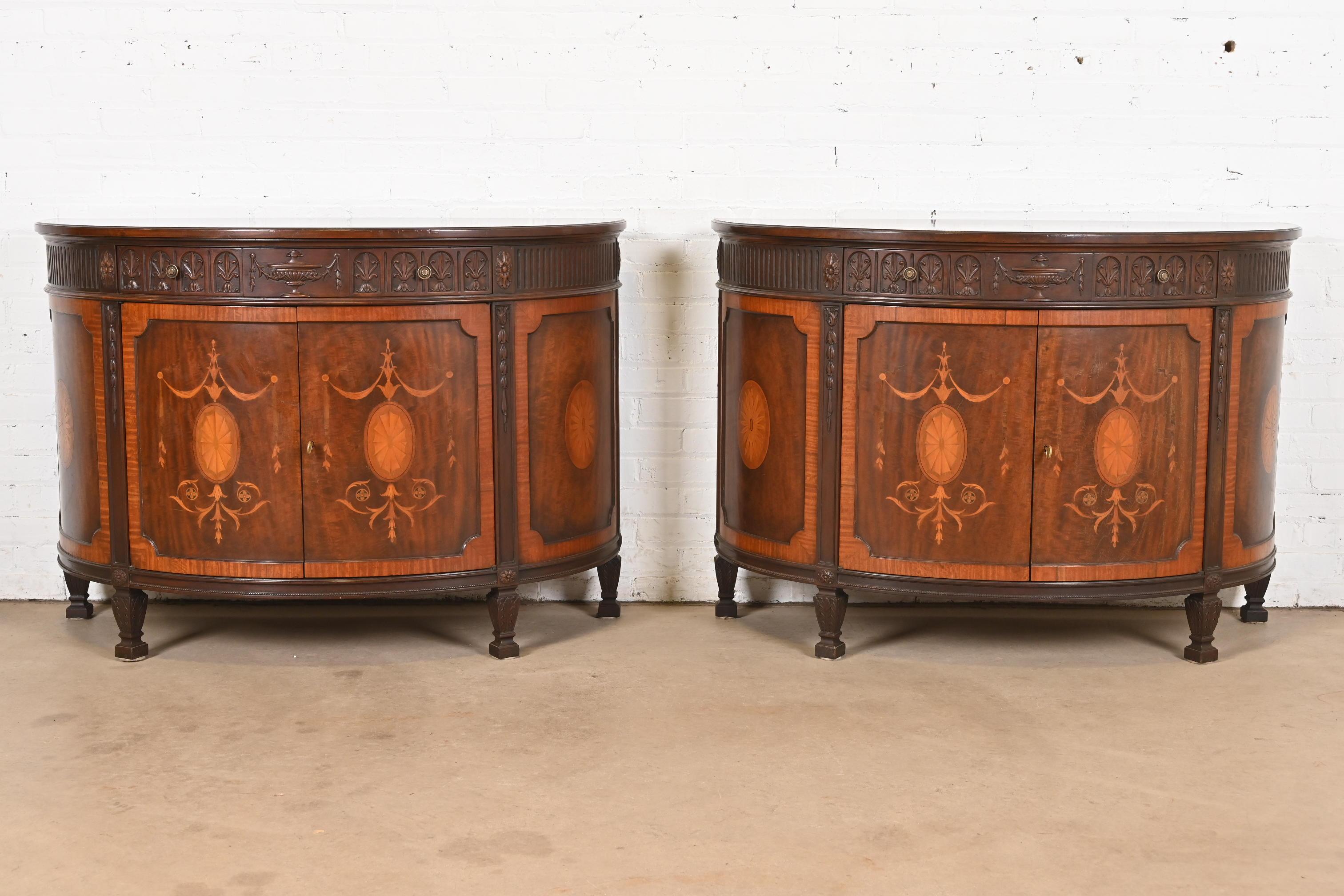 A gorgeous pair of French Regency Louis XVI style demilune cabinets, sideboards, console tables, or bar cabinets

By Baker Furniture

USA, Circa 1960s

Beautiful carved mahogany, with inlaid satinwood marquetry, and original brass hardware. Cabinets