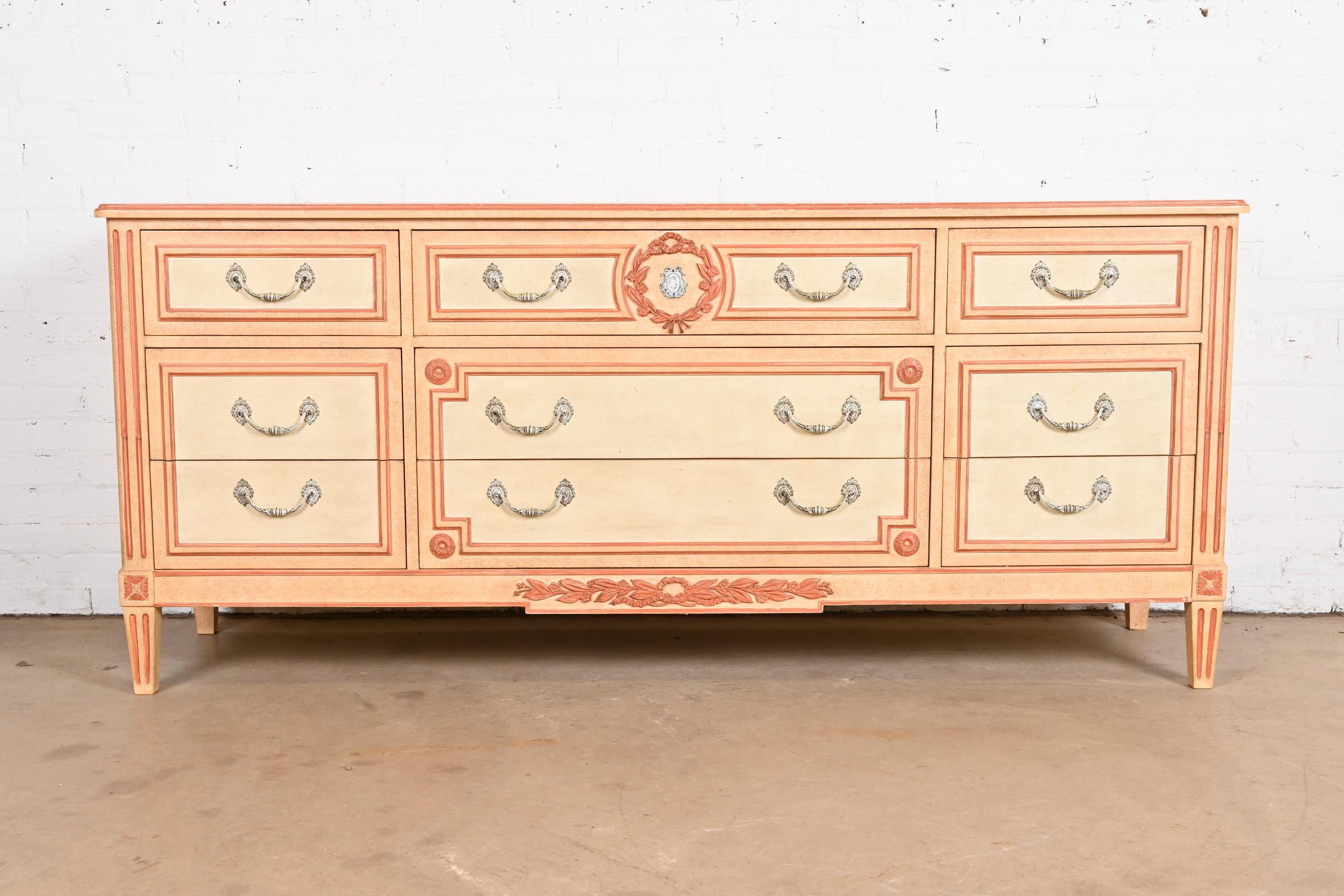 A gorgeous French Regency Louis XVI or Swedish Gustavian style triple dresser or credenza

By Baker Furniture

USA, 1960s

Carved cream painted walnut, with peachy pink trim and accents, and original brass hardware.

Measures: 74.75