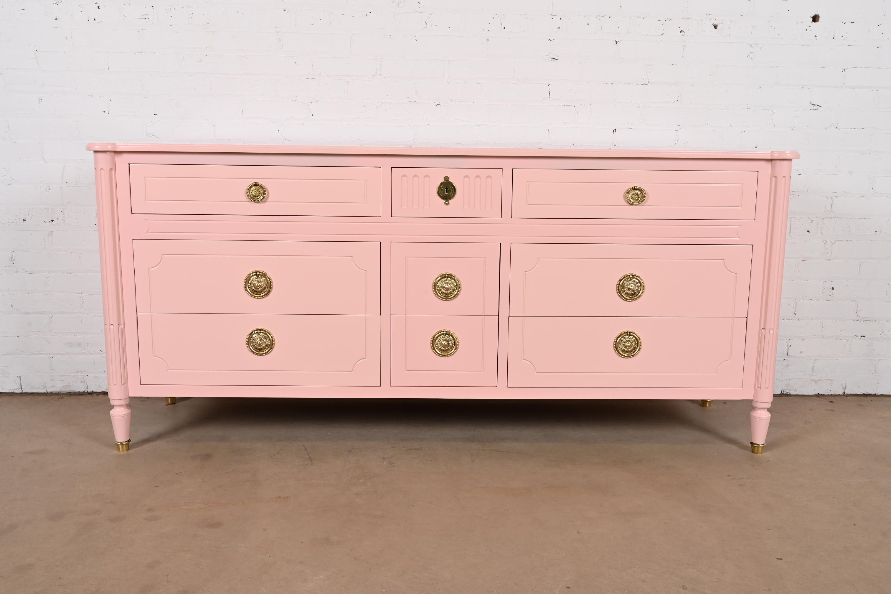 A gorgeous French Regency Louis XVI style nine-drawer triple dresser or credenza

By Baker Furniture

USA, Circa 1960s

Pink lacquered walnut, with original brass hardware.

Measures: 71.5