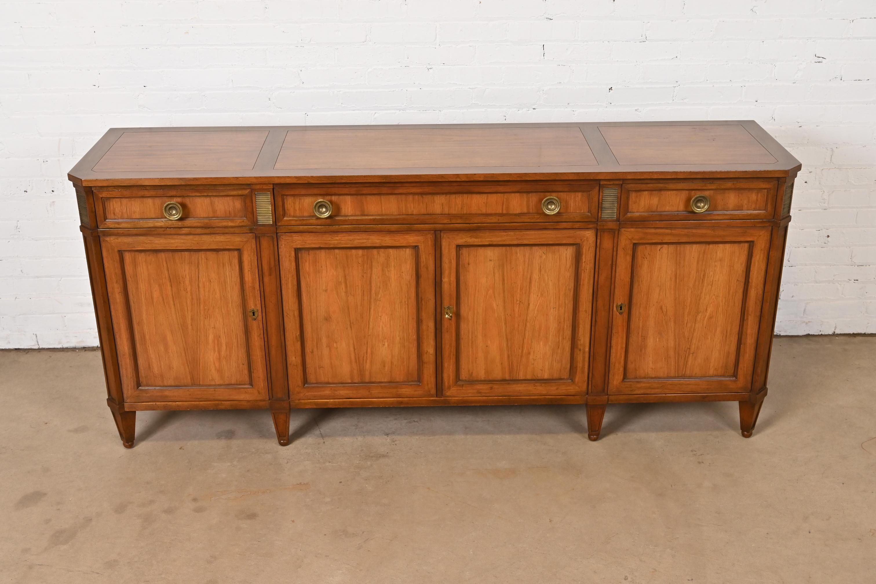 A gorgeous French Regency Louis XVI style sideboard, credenza, or bar cabinet

By Baker Furniture

USA, Circa 1960s

Book-matched rosewood and walnut, with brass accents and hardware. Lower cabinets lock, and original key is included.

Measures: