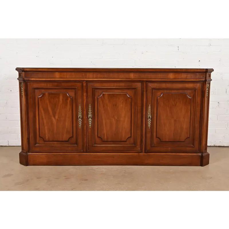 Un precioso aparador, credenza o mueble bar estilo Luis XVI de la Regencia francesa de mediados de siglo

Por Baker Furniture

EE.UU., alrededor de 1960

De nogal tallado, con preciosa tapa de nogal burilado a juego con el libro, y herrajes
