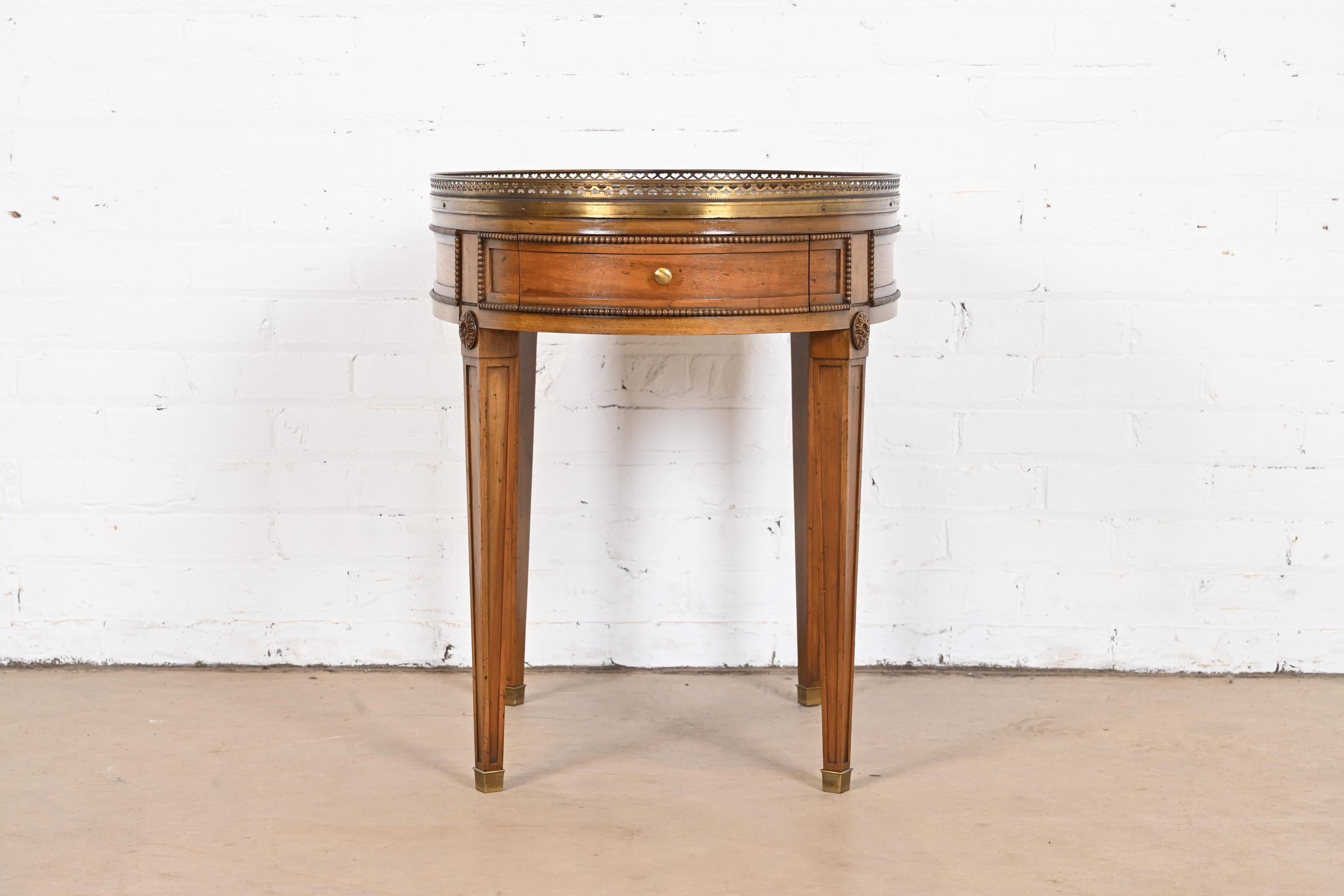 A gorgeous Neoclassical or French Regency Louis XVI style tea table or occasional side table

By Baker Furniture

USA, Circa 1960s

Carved walnut, with beautiful book-matched burled walnut top, and brass gallery.

Measures: 20