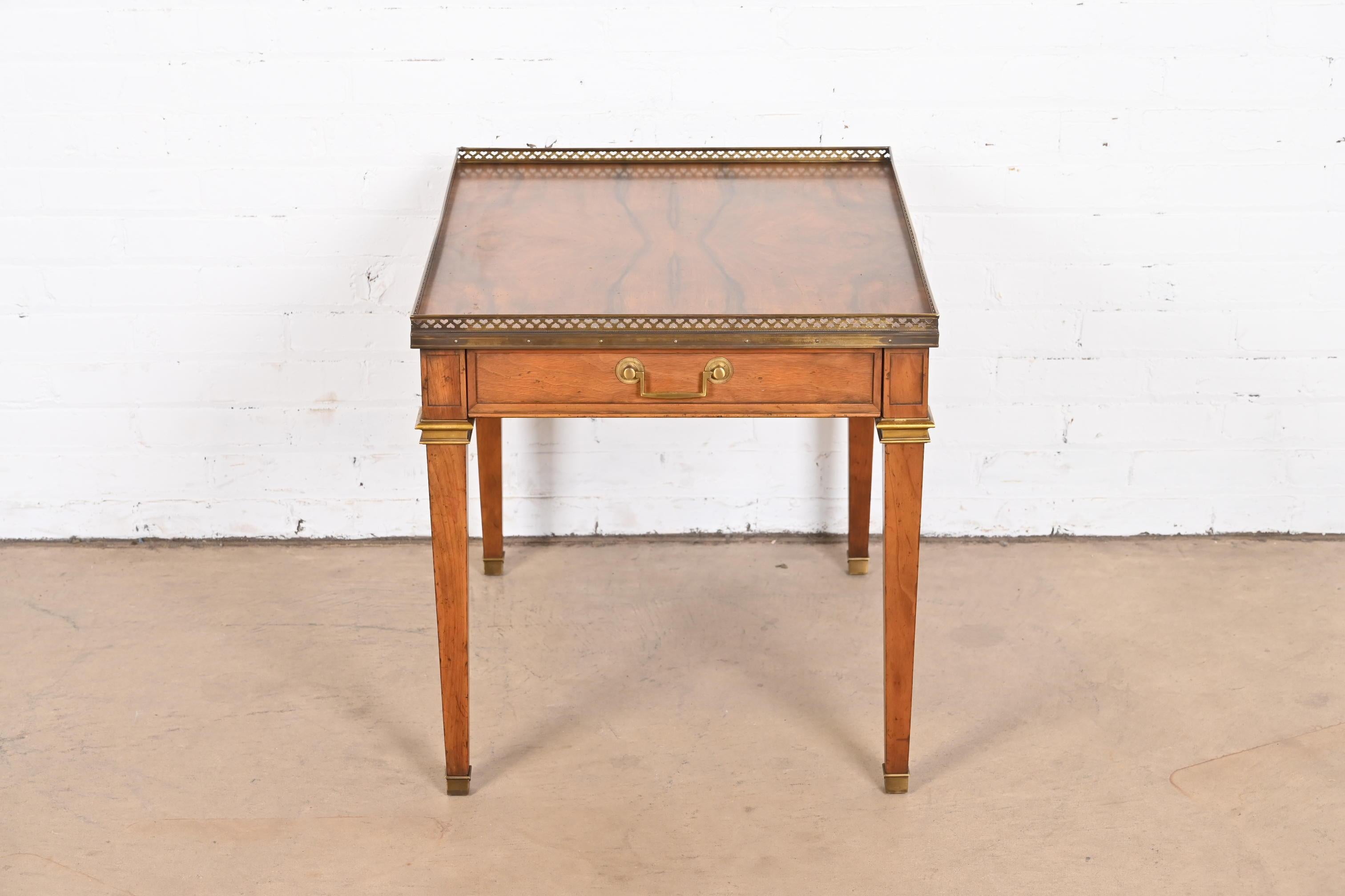 A gorgeous Neoclassical or French Regency Louis XVI style tea table or occasional side table

By Baker Furniture

USA, Circa 1960s

Carved walnut, with beautiful book-matched burled walnut top, and brass hardware and gallery.

Measures: 22
