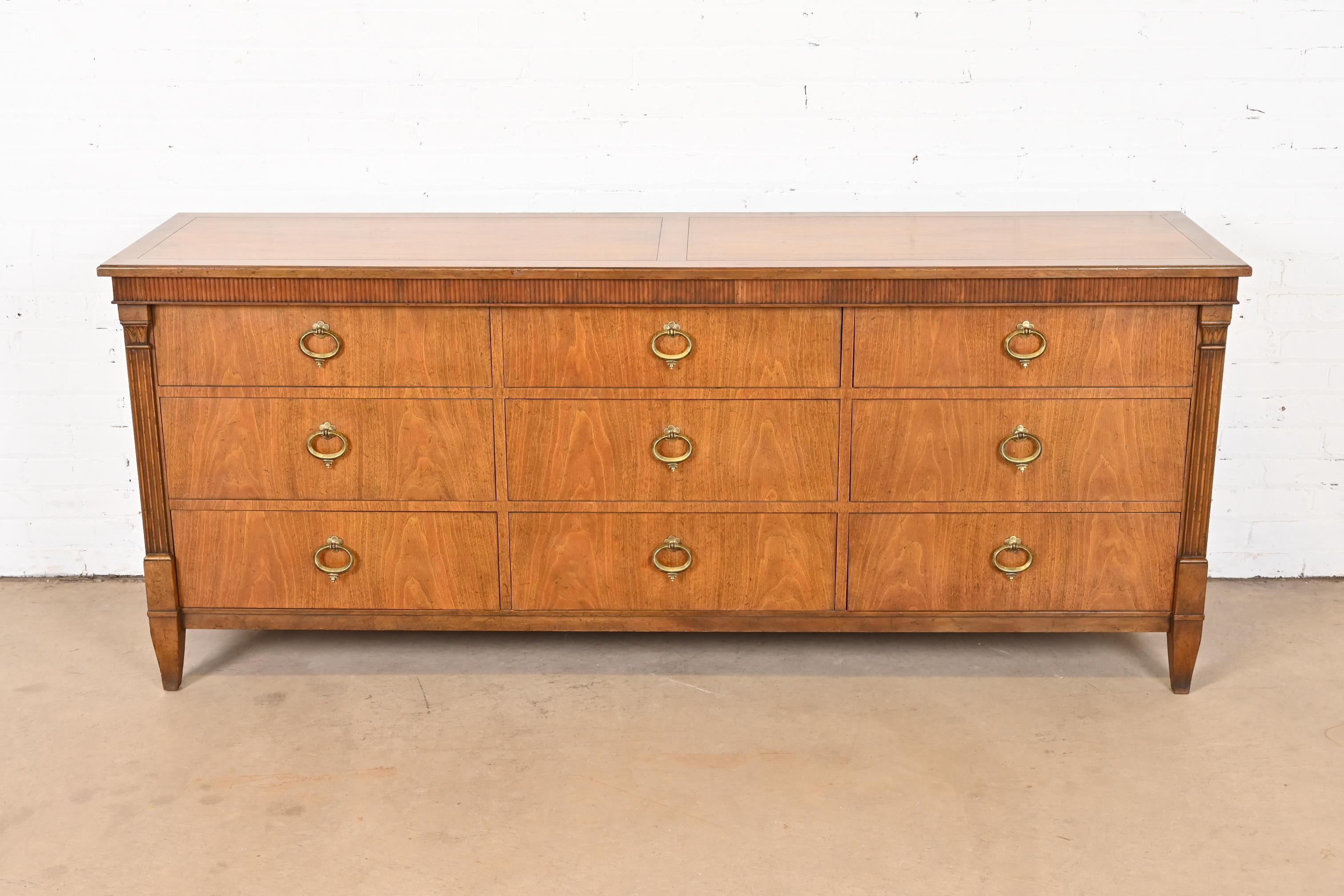 A gorgeous French Regency Louis XVI or Neoclassical style nine-drawer dresser or credenza

By Baker Furniture

USA, Circa 1960s

Beautiful book-matched carved walnut, with original brass hardware.

Measures: 75.75