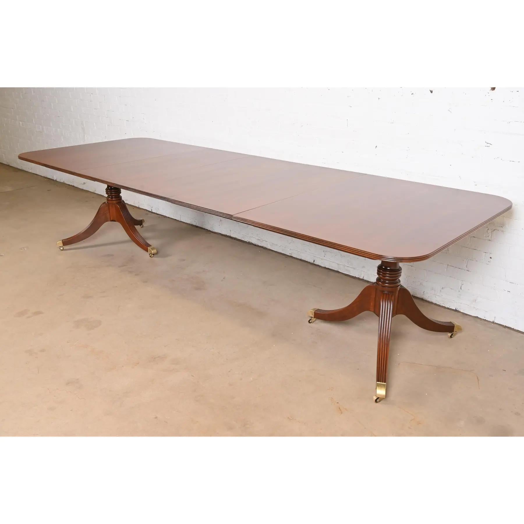 An exceptional Georgian or Regency style double pedestal extension dining table

By Baker Furniture

USA, Circa 1980s

Gorgeous book-matched banded cherry wood top, with carved solid cherry wood pedestals, and brass-capped feet on brass