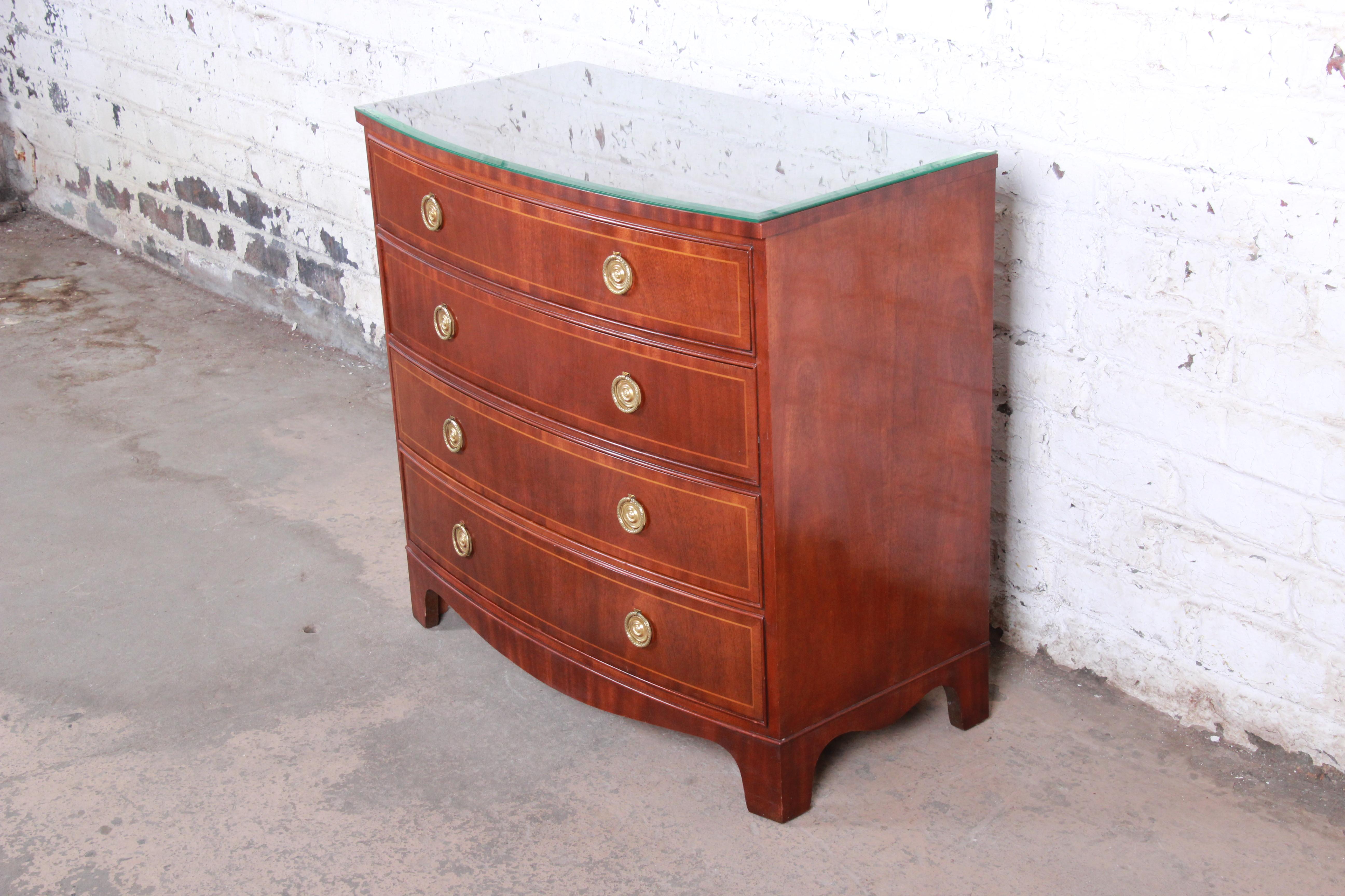 Baker Furniture Georgian banded mahogany bow front four-drawer chest of drawers

Made by Baker Furniture

USA, circa 1980s

Book-matched mahogany and satinwood banding and brass ring drawer pulls and beveled glass top

Measures: 34