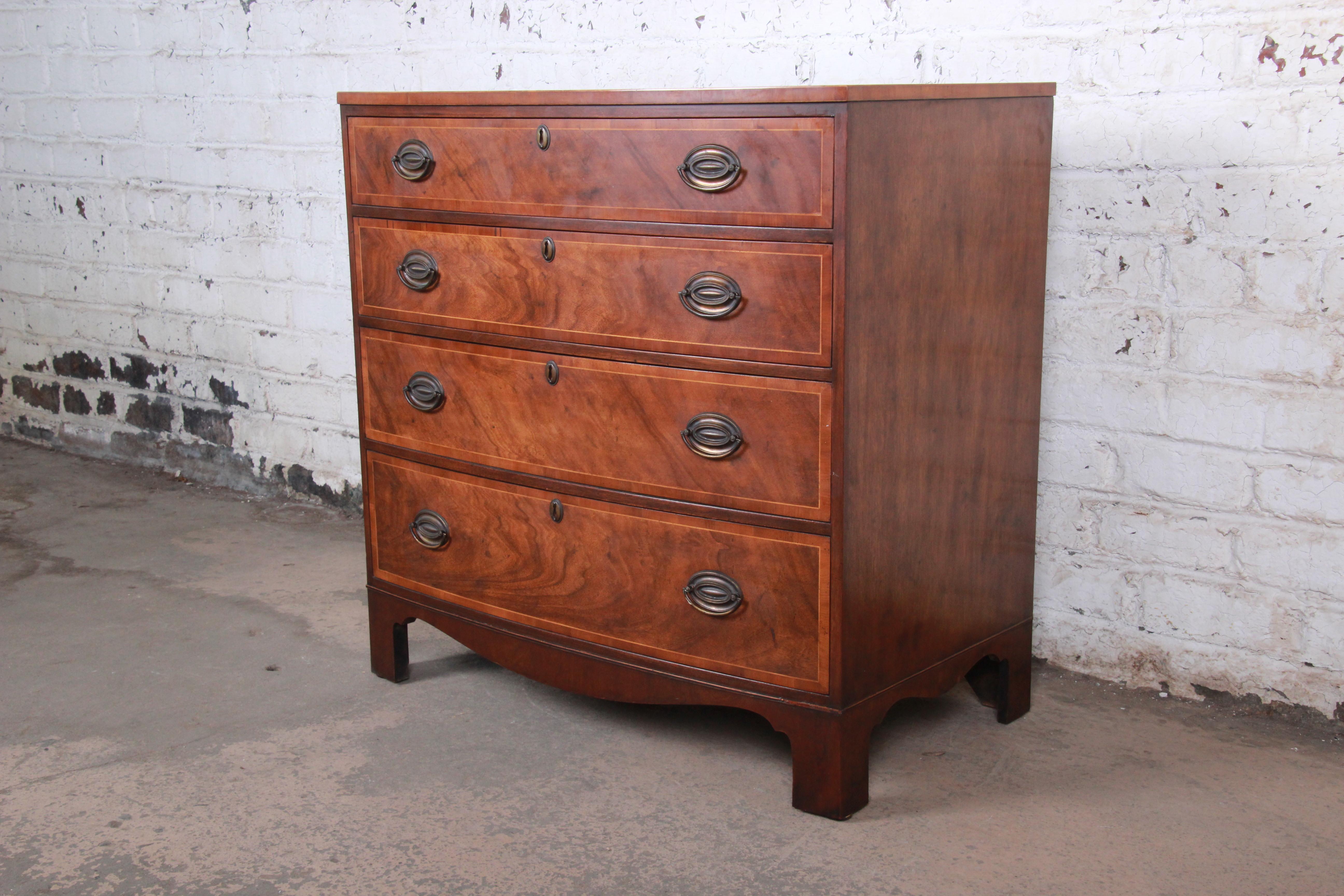 A gorgeous Georgian banded mahogany bow front four-drawer bachelor chest of drawers or commode

By Baker Furniture

USA, circa 1960s

Book-matched mahogany + satinwood banding + brass ring drawer pulls

Measures: 35.25