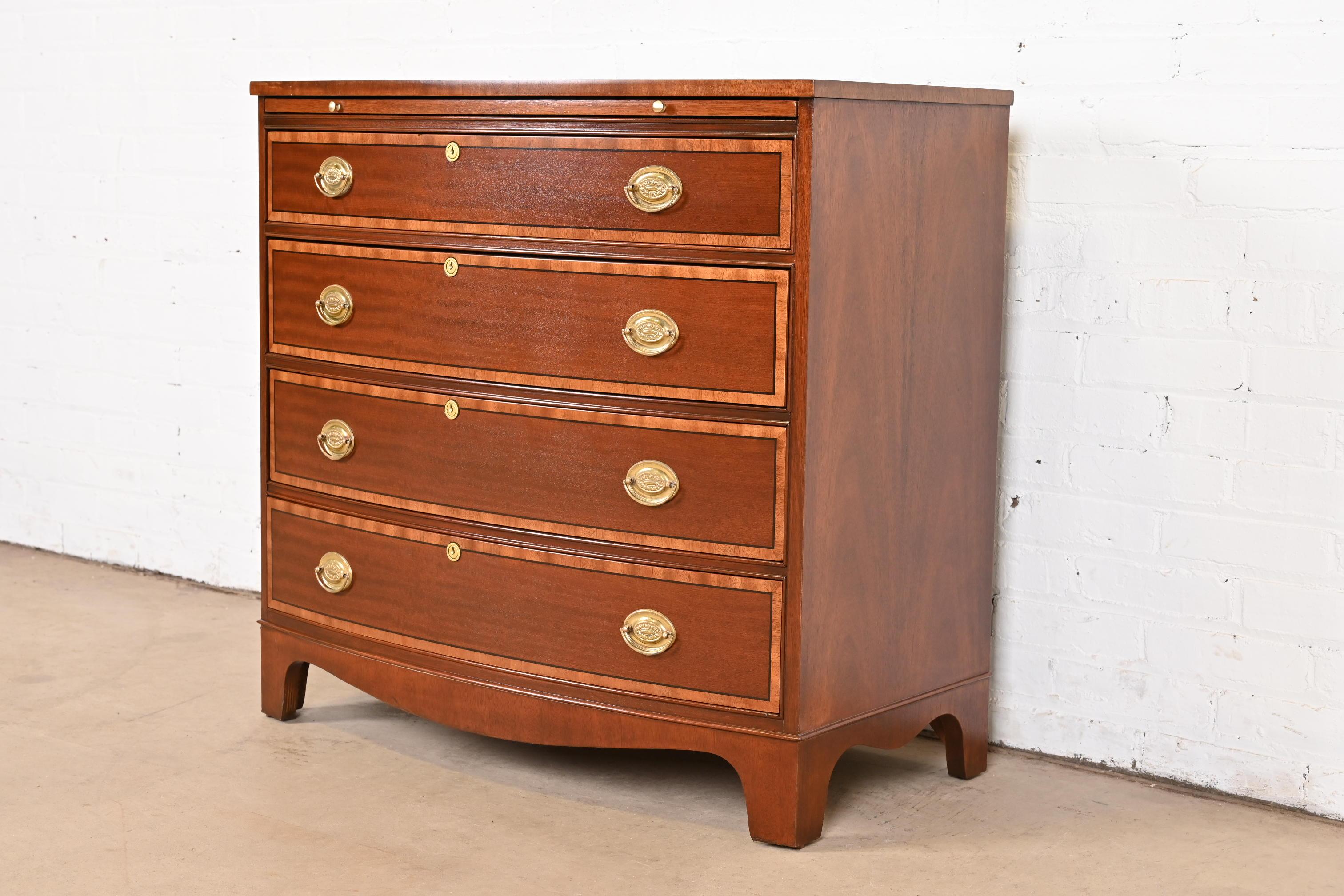 A gorgeous Georgian or Chippendale style bow front four-drawer commode, dresser, or chest of drawers

By Baker Furniture

USA, Circa 1980s

Mahogany, with satinwood banding, and original brass hardware.

Measures: 34