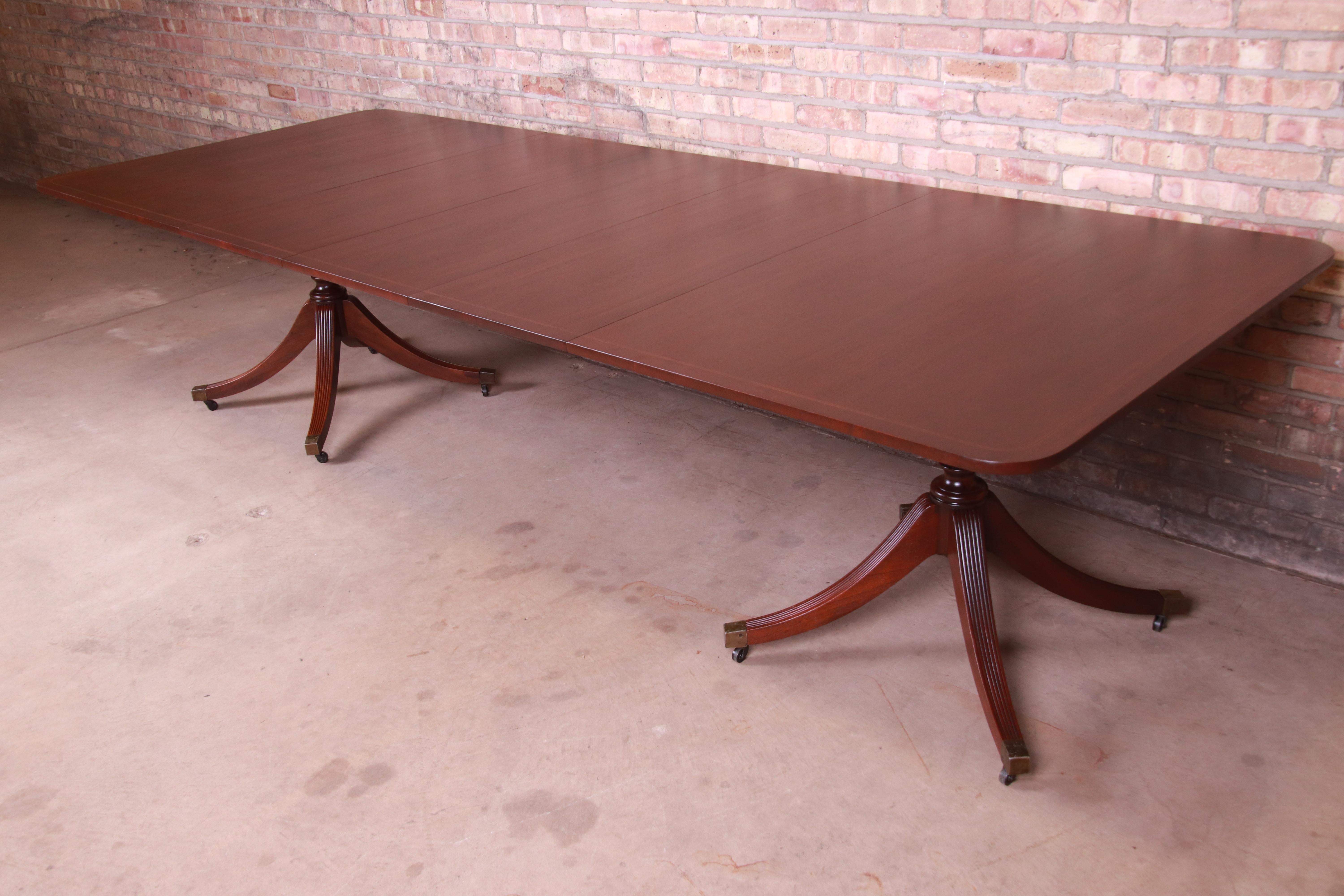 An exceptional Georgian style extension double pedestal dining table

By Baker Furniture

USA, circa 1950s

Book-matched mahogany with satinwood string inlay, carved solid mahogany pedestals, and brass-capped feet.

Measures: 67.75