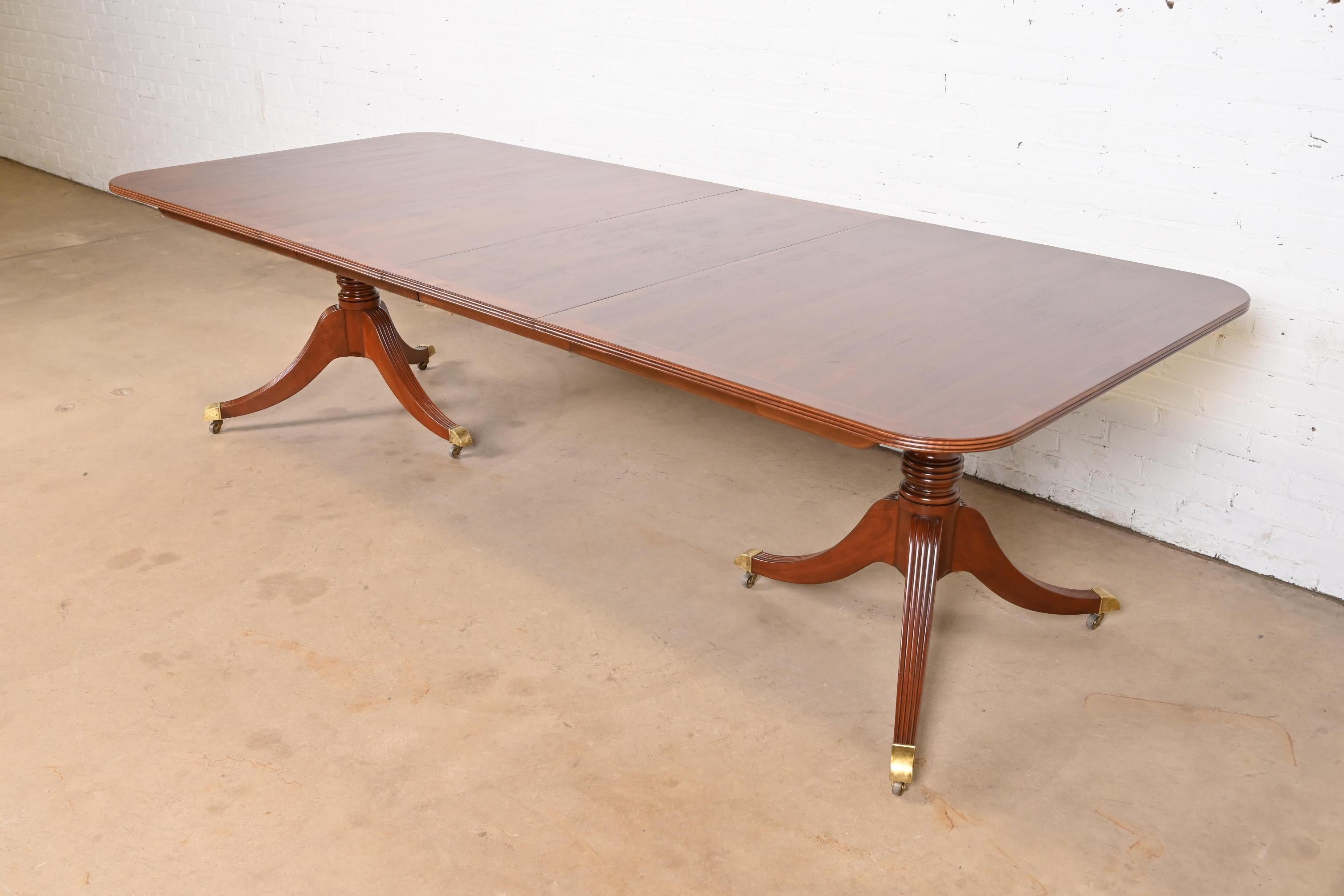 Exceptionnelle table à manger à rallonge à double piédestal de style Géorgien ou Régence.

Par Baker Furniture

USA, Circa Late 20th Century

Magnifique acajou, avec incrustation de cordes en bois de satin, bandeau en bois d'if anglais, piédestaux