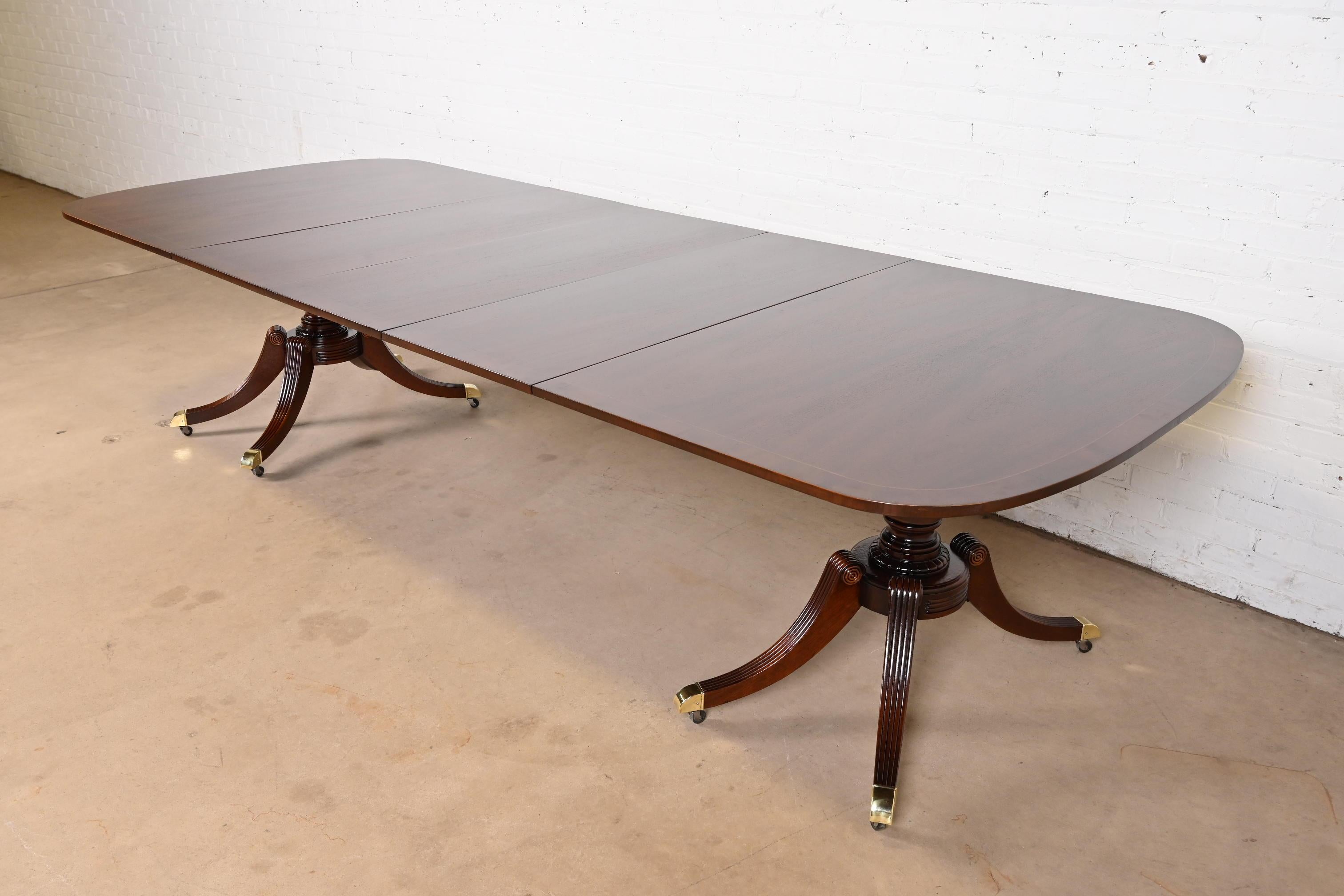 Exceptionnelle table à manger à rallonge à double piédestal de style Géorgien ou Régence.

Par Baker Furniture

États-Unis, vers les années 1940

Magnifique plateau d'acajou bagué, avec des piédestaux en acajou sculpté, et des pieds coiffés de