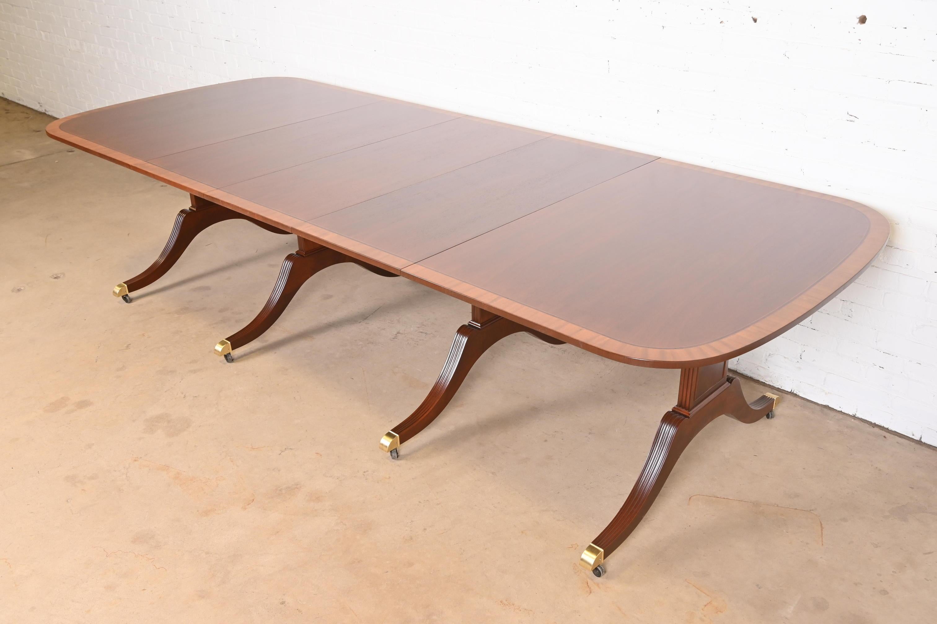 A gorgeous Georgian or Regency style pedestal extension dining table

By Baker Furniture

USA, Circa 1980s

Beautiful mahogany, with satinwood banding, carved solid mahogany pedestals, and brass-capped feet on casters.

Measures: 68