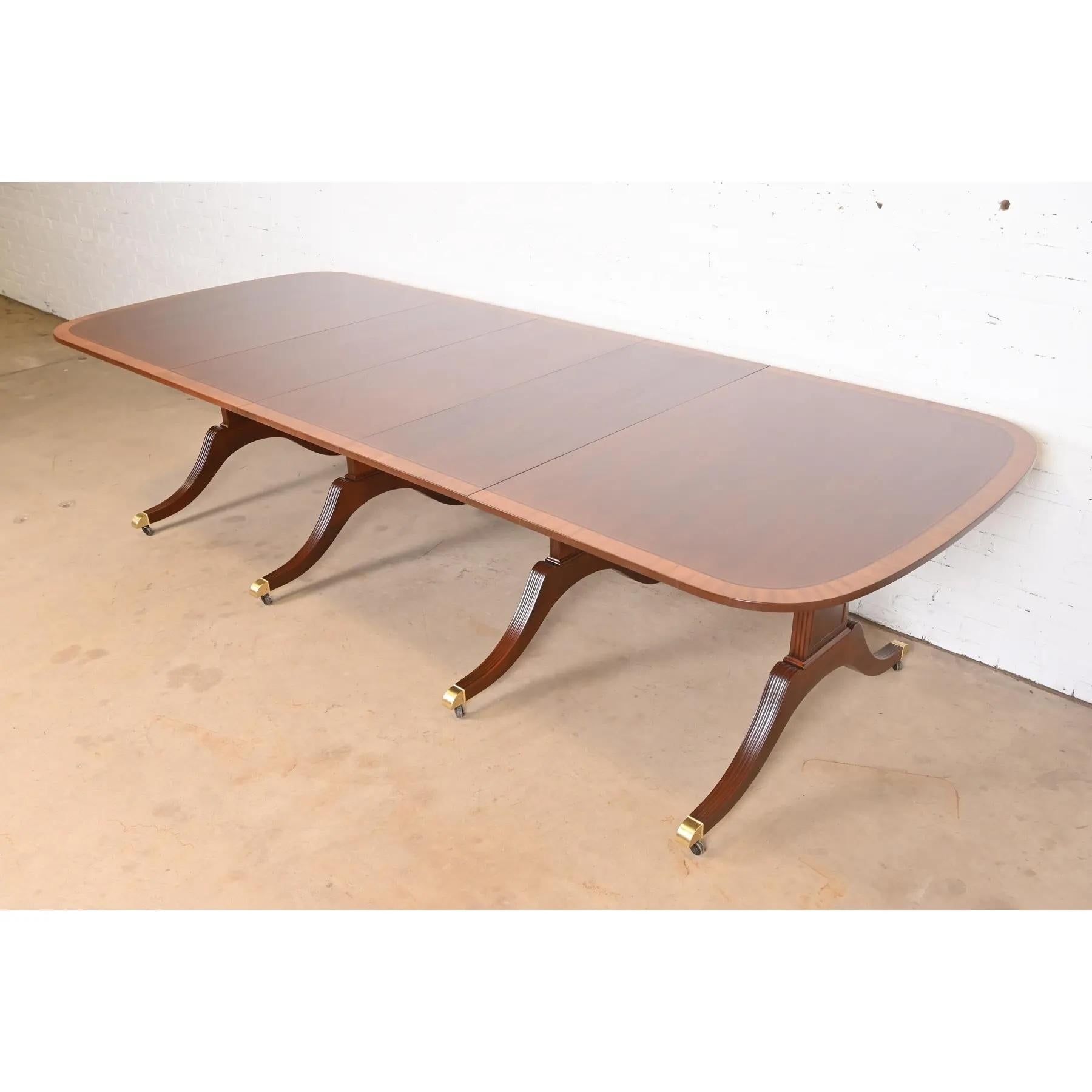 Ein prächtiger Esstisch im georgianischen oder Regency-Stil mit Sockelverlängerung

Von Baker Furniture

USA, ca. 1980er Jahre

Wunderschönes Mahagoni, mit Satinholzbändern, geschnitzten Sockeln aus massivem Mahagoni und Füßen mit Messingkappen auf