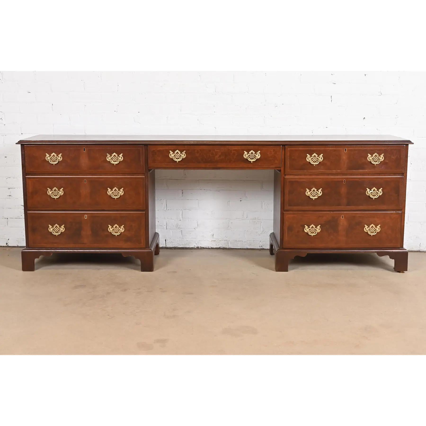 Una maestosa scrivania credenza direzionale in stile georgiano o Chippendale

Da Baker Furniture

USA, Circa anni '50

Cassa in noce, con splendidi frontali dei cassetti in noce burlato e tiretti originali in ottone.

Misure: 88,88