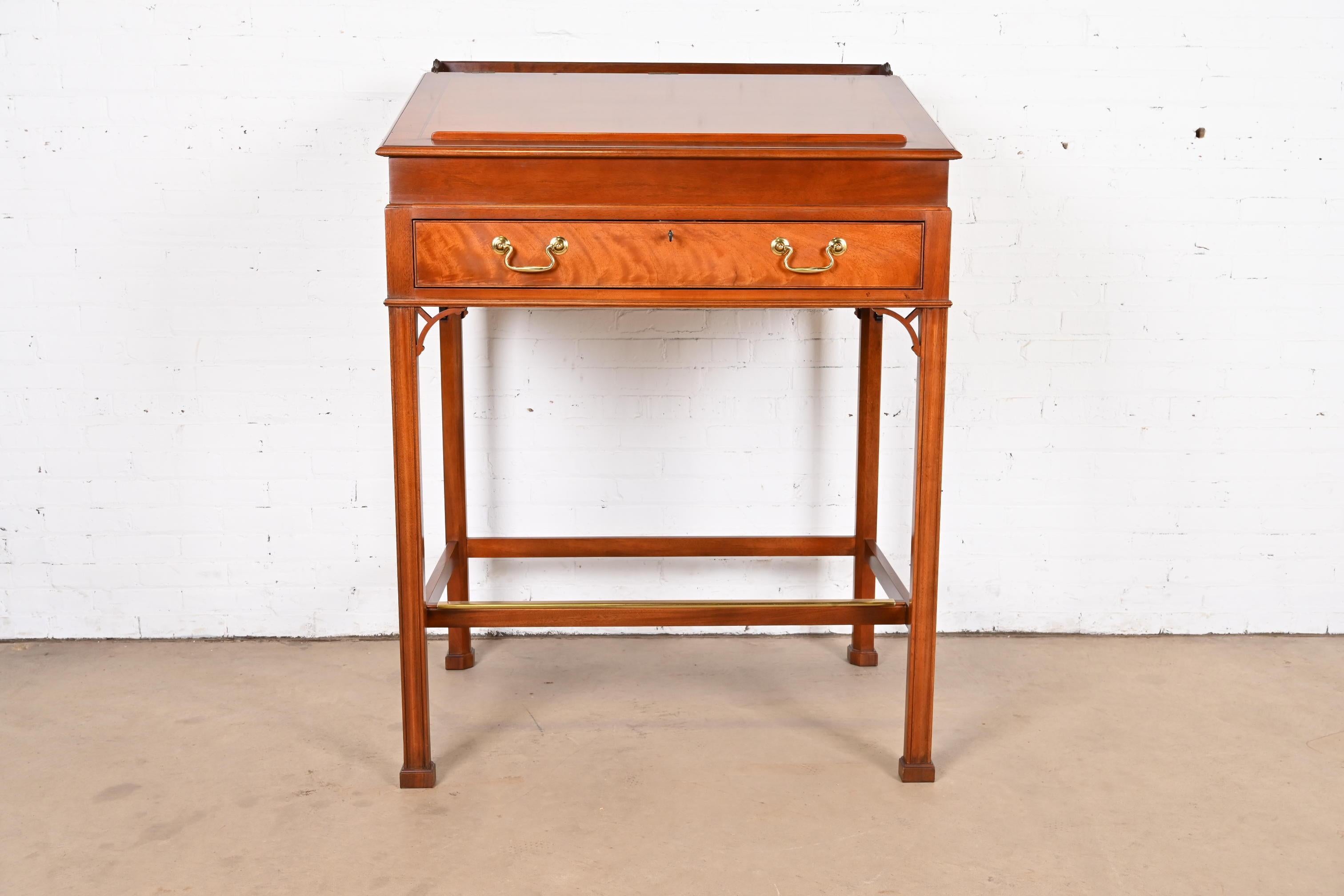A gorgeous Georgian or Chippendale style slant front standing desk or architect's desk

By Baker Furniture

USA, Late 20th Century

Carved mahogany, with original brass hardware.

Measures: 39.75