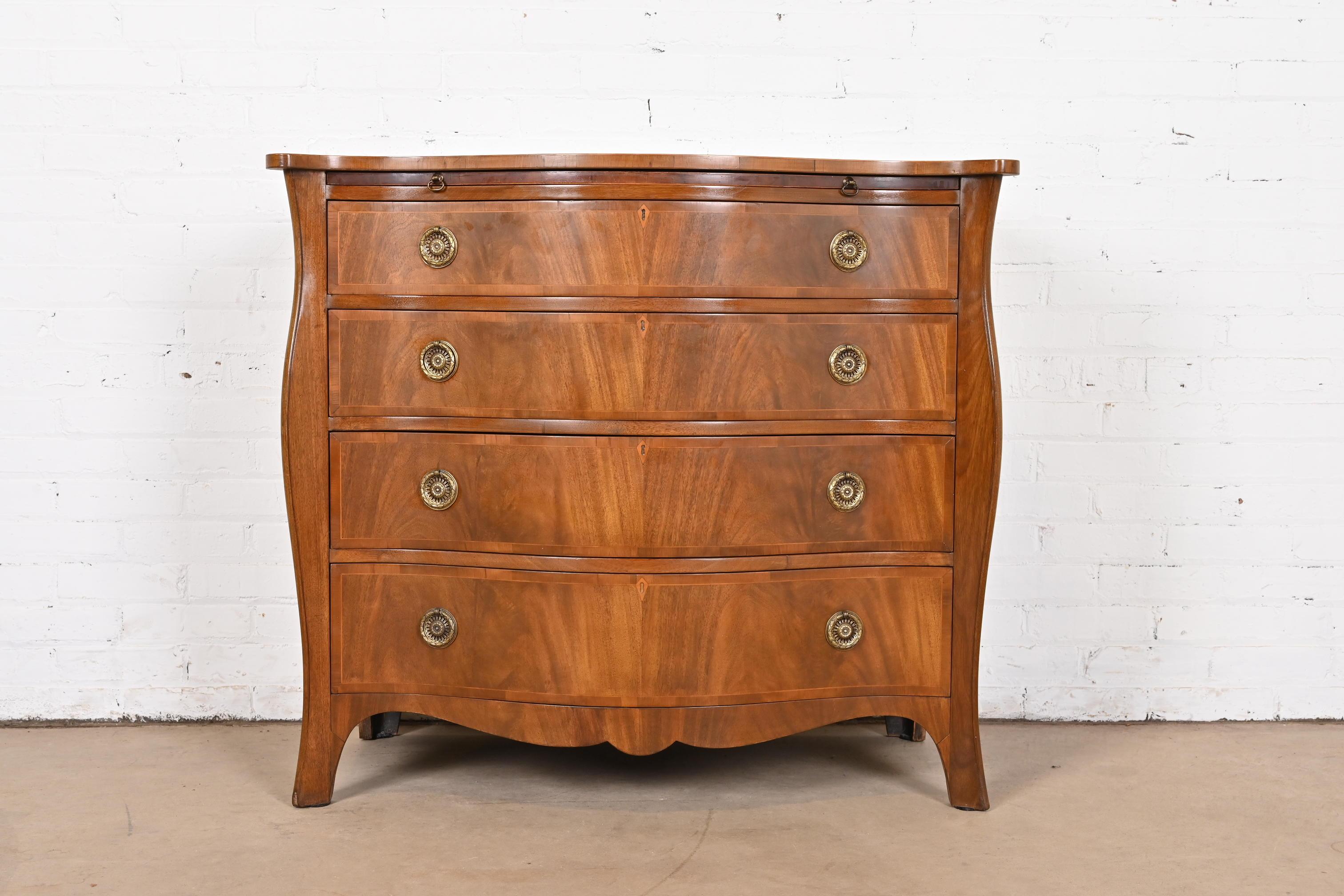 An exceptional Georgian or Regency style flame mahogany dresser or chest of drawers

By Baker Furniture

USA, Circa 1940s

Beautiful book-matched flame mahogany, with embossed leather pull-out writing or dressing table, and original brass