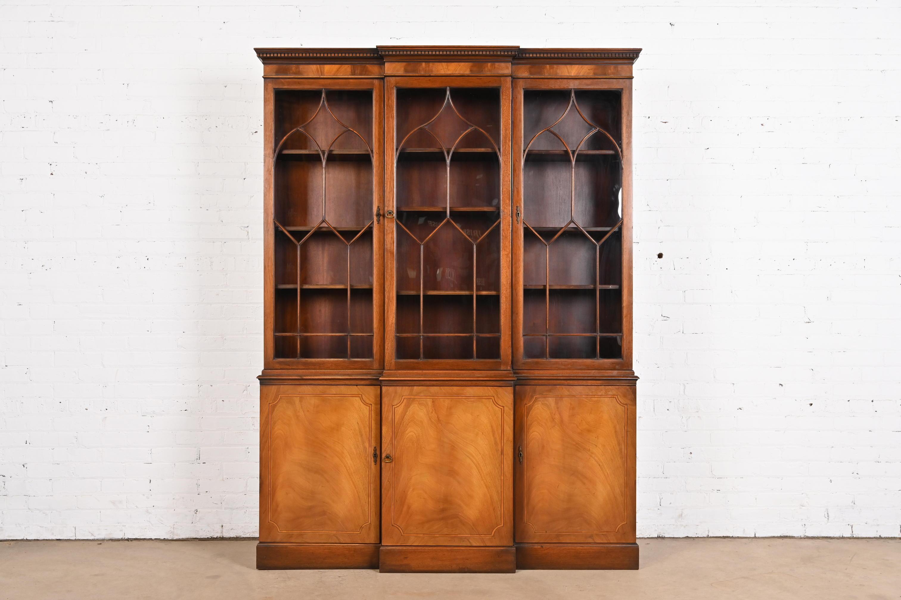 A gorgeous Georgian or Chippendale style breakfront bookcase or dining cabinet 

By Baker Furniture

USA, Circa 1940s

Book-matched flame mahogany, with satinwood inlay, mullioned glass front doors, and original brass hardware. Cabinets lock, and