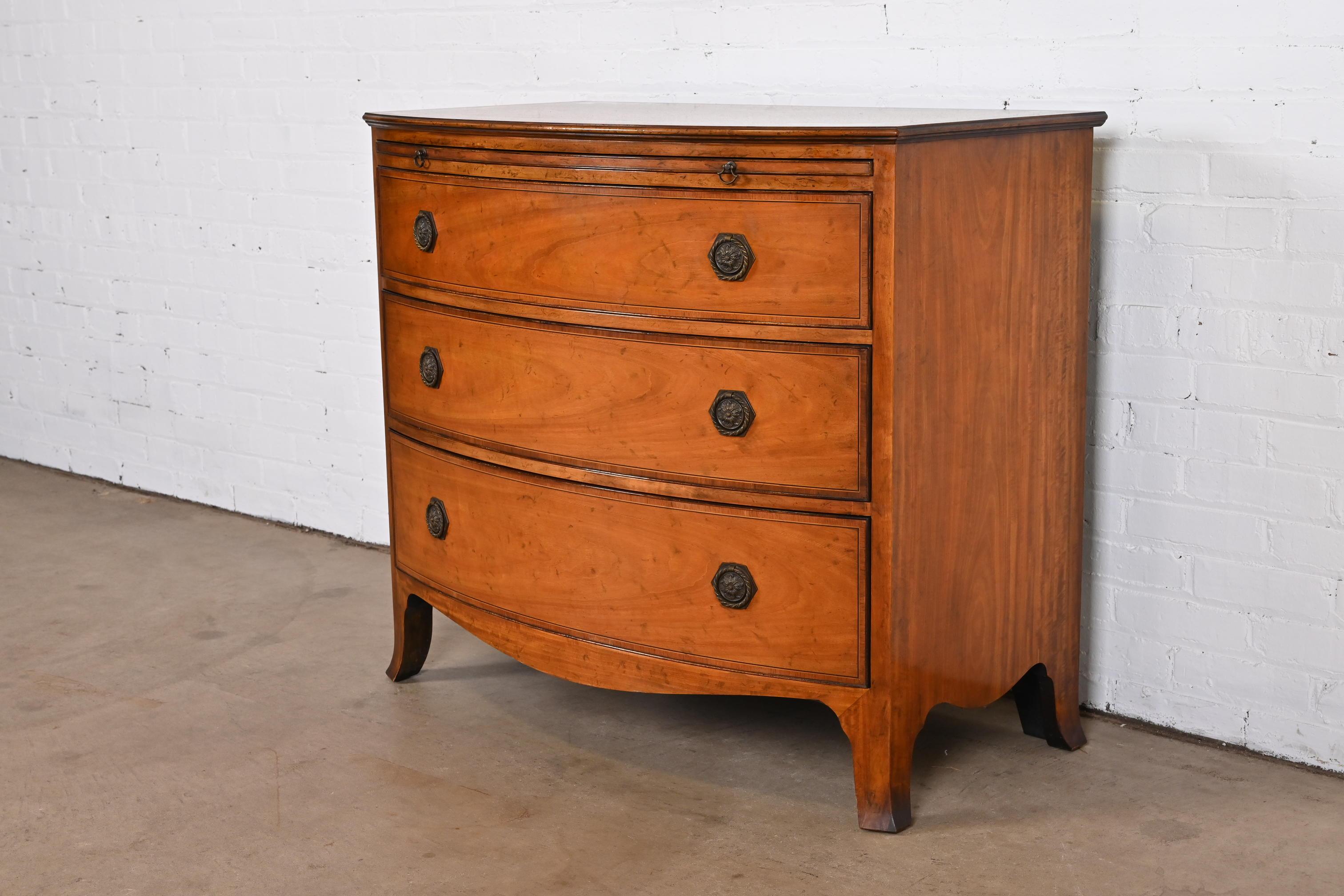 A gorgeous Georgian bow front dresser, commode, or bachelor chest of drawers

By Baker Furniture

USA, Circa 1950s

Mahogany, with satinwood and ebony string inlay, embossed leather pull-out trays, and original brass hardware.

Measures: 39