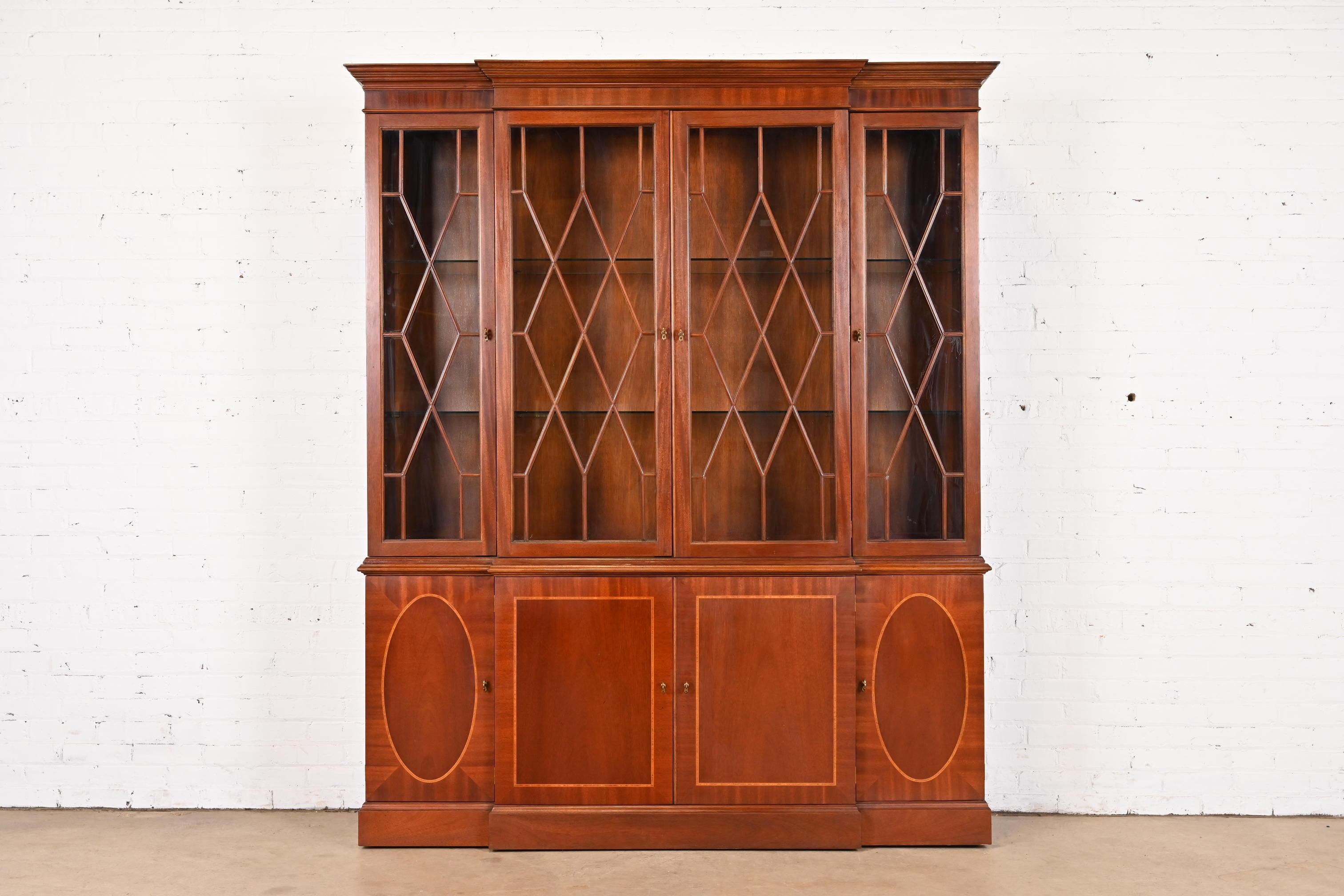 A gorgeous Georgian or Chippendale style lighted breakfront bookcase or dining cabinet

By Baker Furniture

USA, Late 20th Century

Mahogany, with satinwood inlay, mullioned glass front doors, glass shelves, and original brass hardware. Lights have