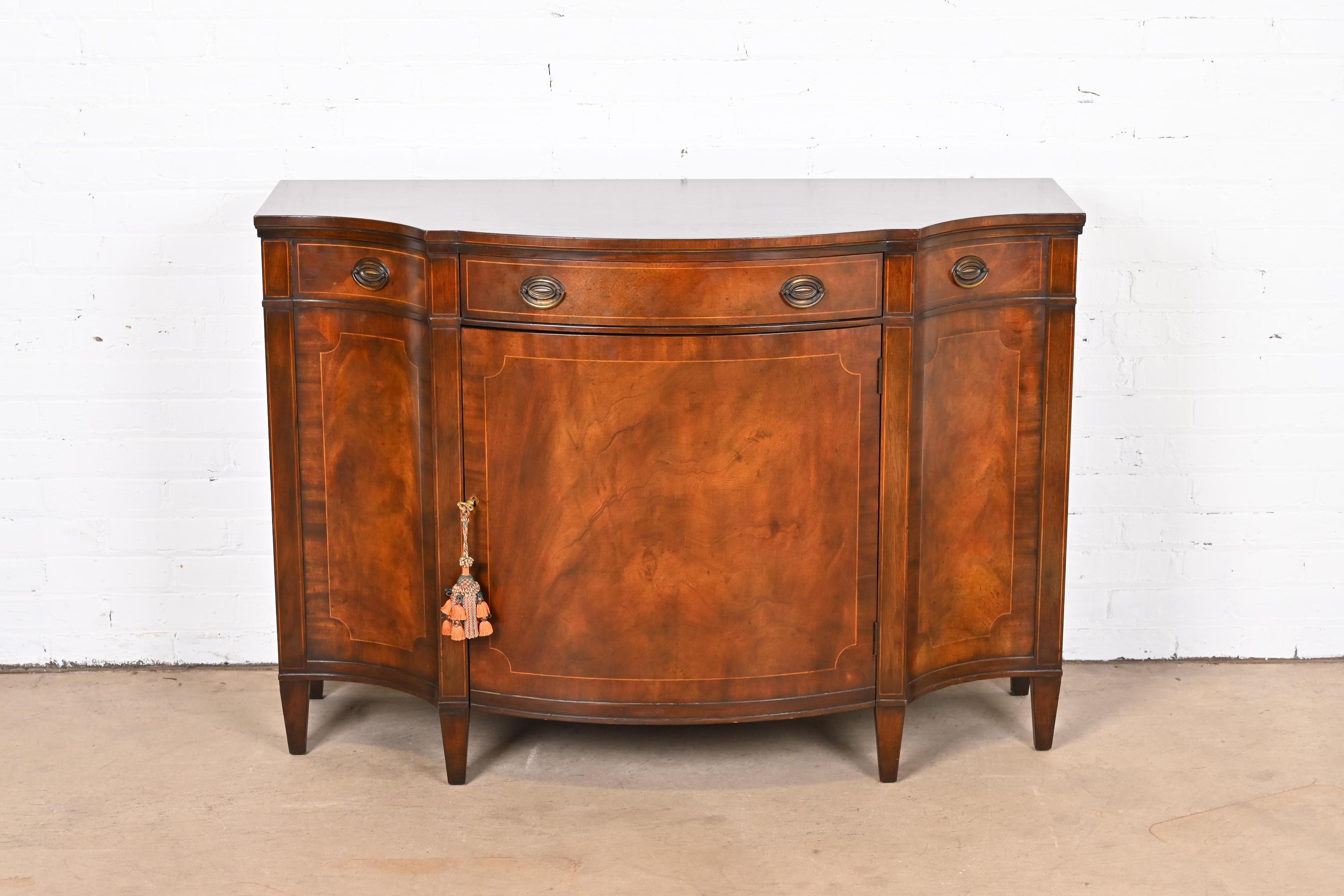 A gorgeous Georgian sideboard, credenza, or bar cabinet

By Baker Furniture

USA, Circa 1950s

Flame mahogany, with satinwood string inlay and original brass hardware. Cabinet locks, and key is included.

Measures: 48