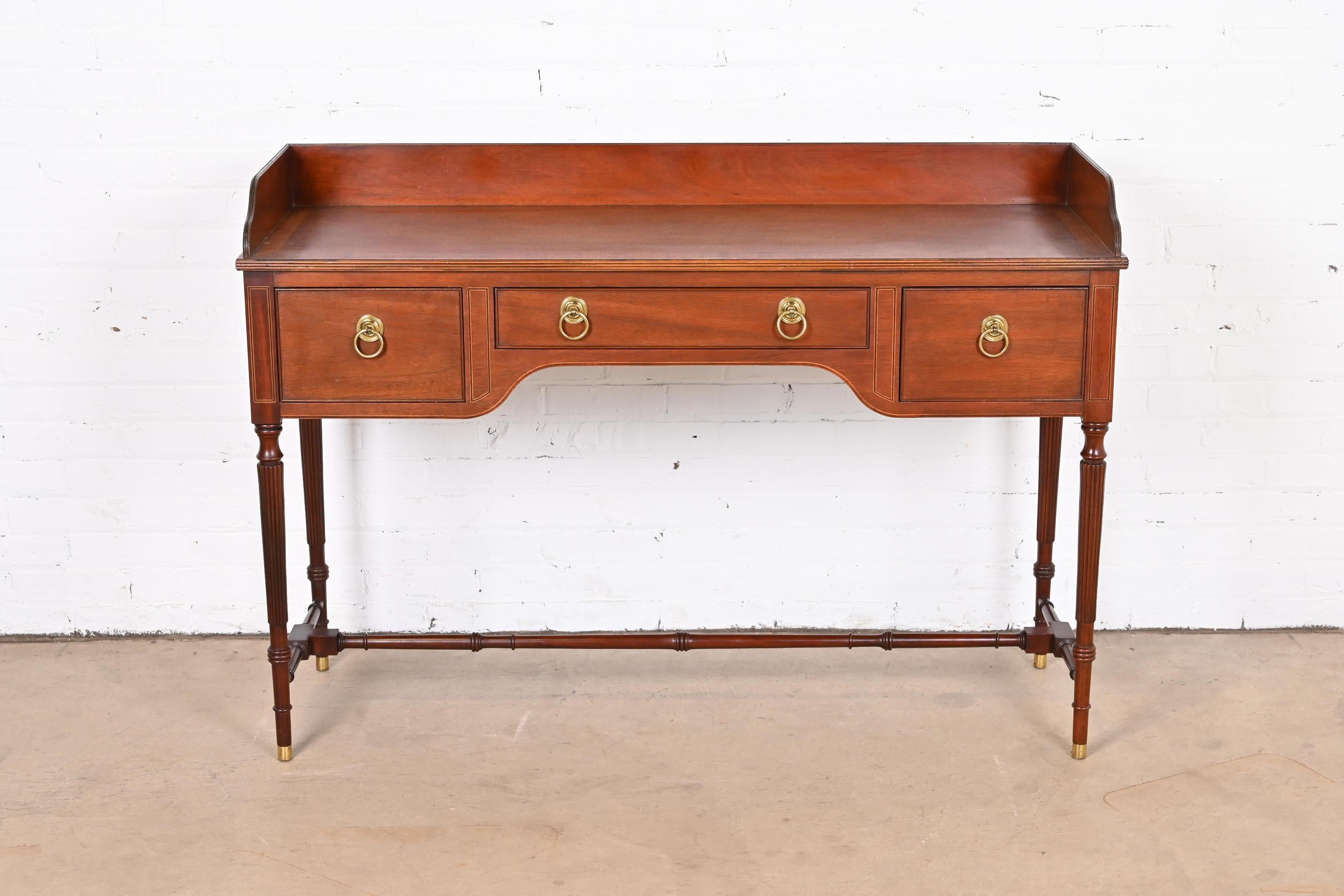 An exceptional Georgian style sideboard or bar server

by Baker Furniture.

USA, Circa 1980s.

Carved mahogany, with satinwood string inlay, original brass hardware, and brass-capped feet.

Measures: 52