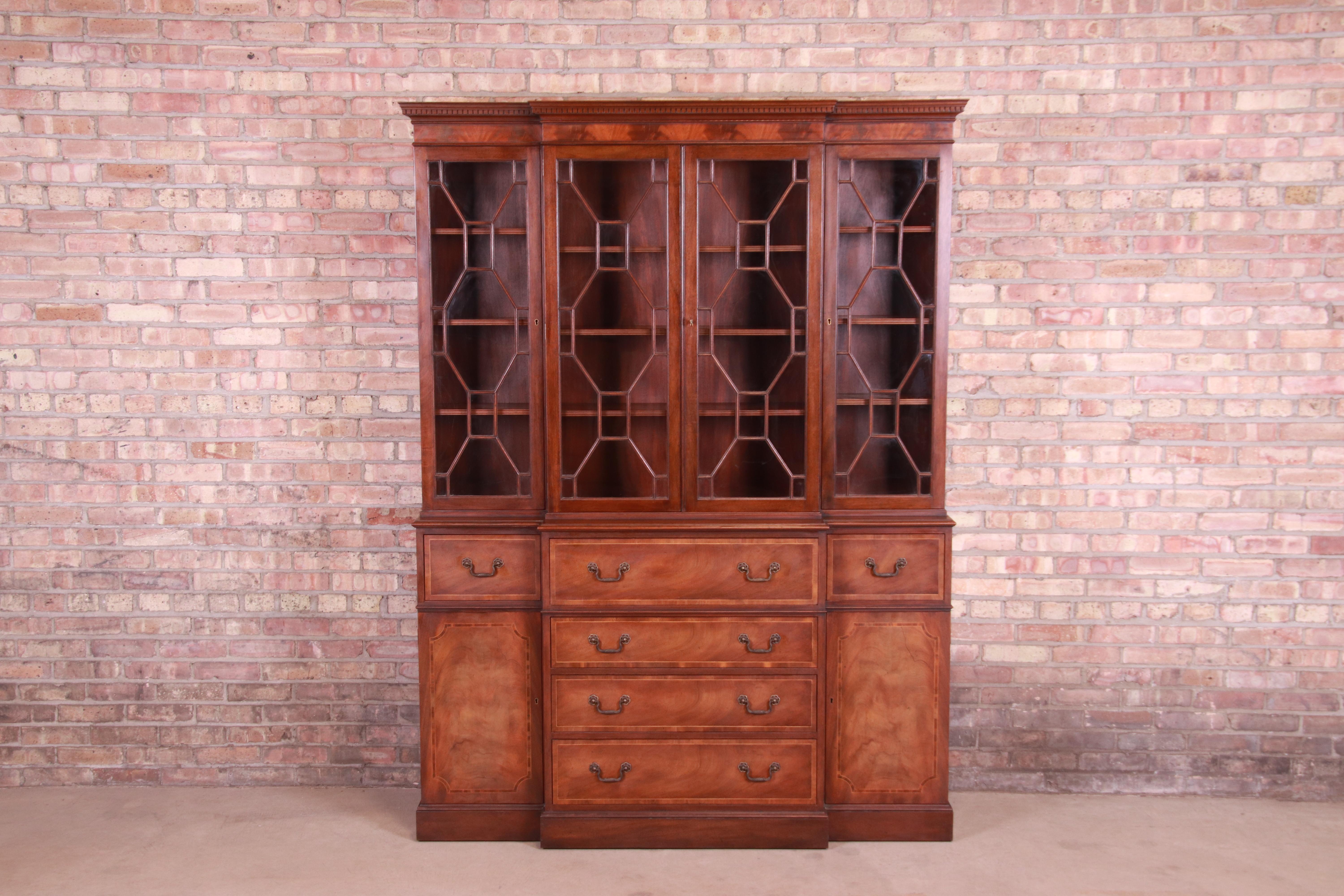 A gorgeous English Georgian style breakfront bookcase cabinet with drop-front secretary desk

By Baker Furniture

USA, mid-20th century

Mahogany, with mullioned glass front doors, original brass hardware, and embossed leather writing