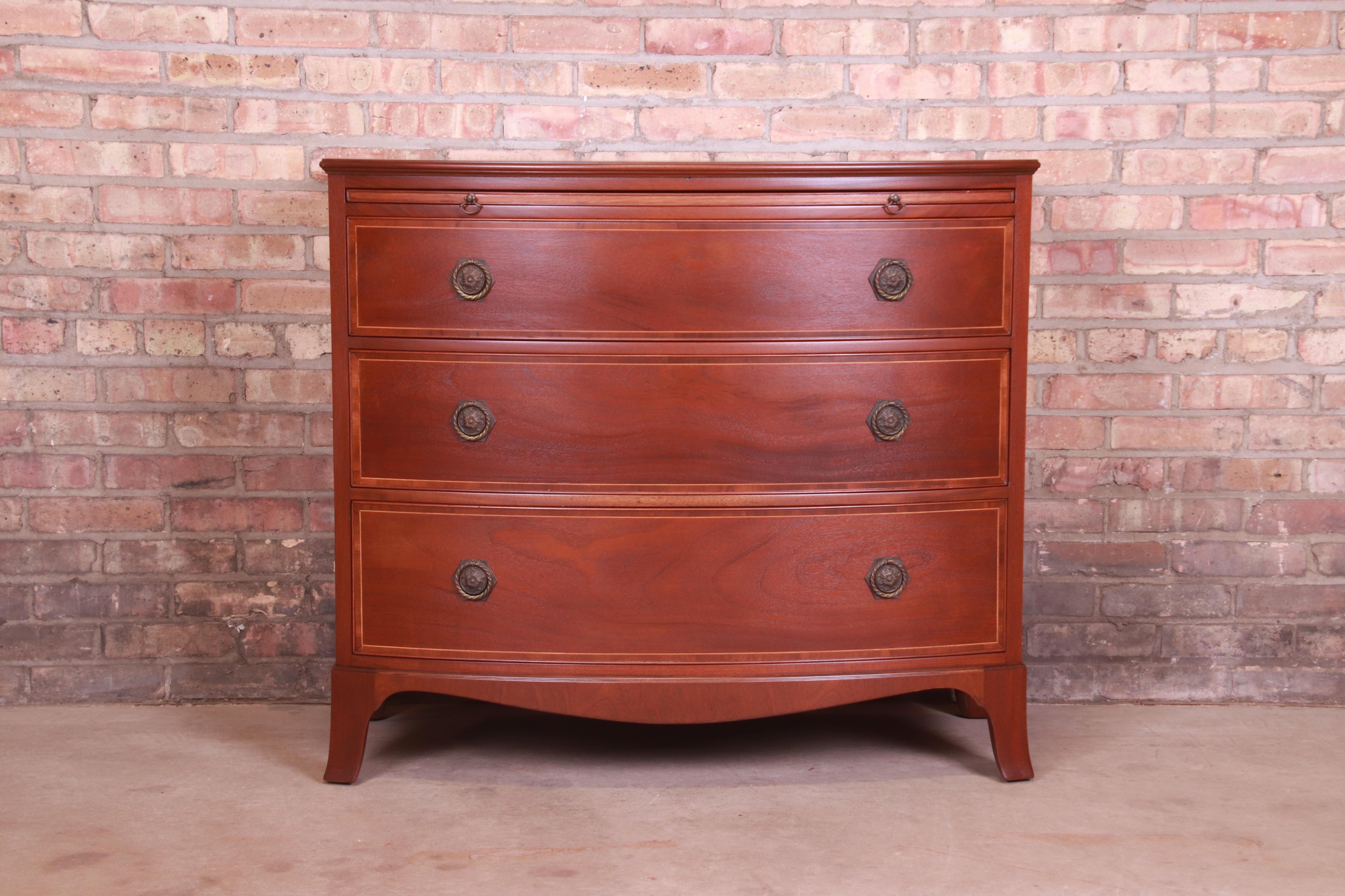 A gorgeous Georgian style bow front three-drawer chest of drawers or commode

By Baker Furniture

USA, Circa 1960s

Mahogany, with satinwood string inlay and original brass hardware.

Measures: 39