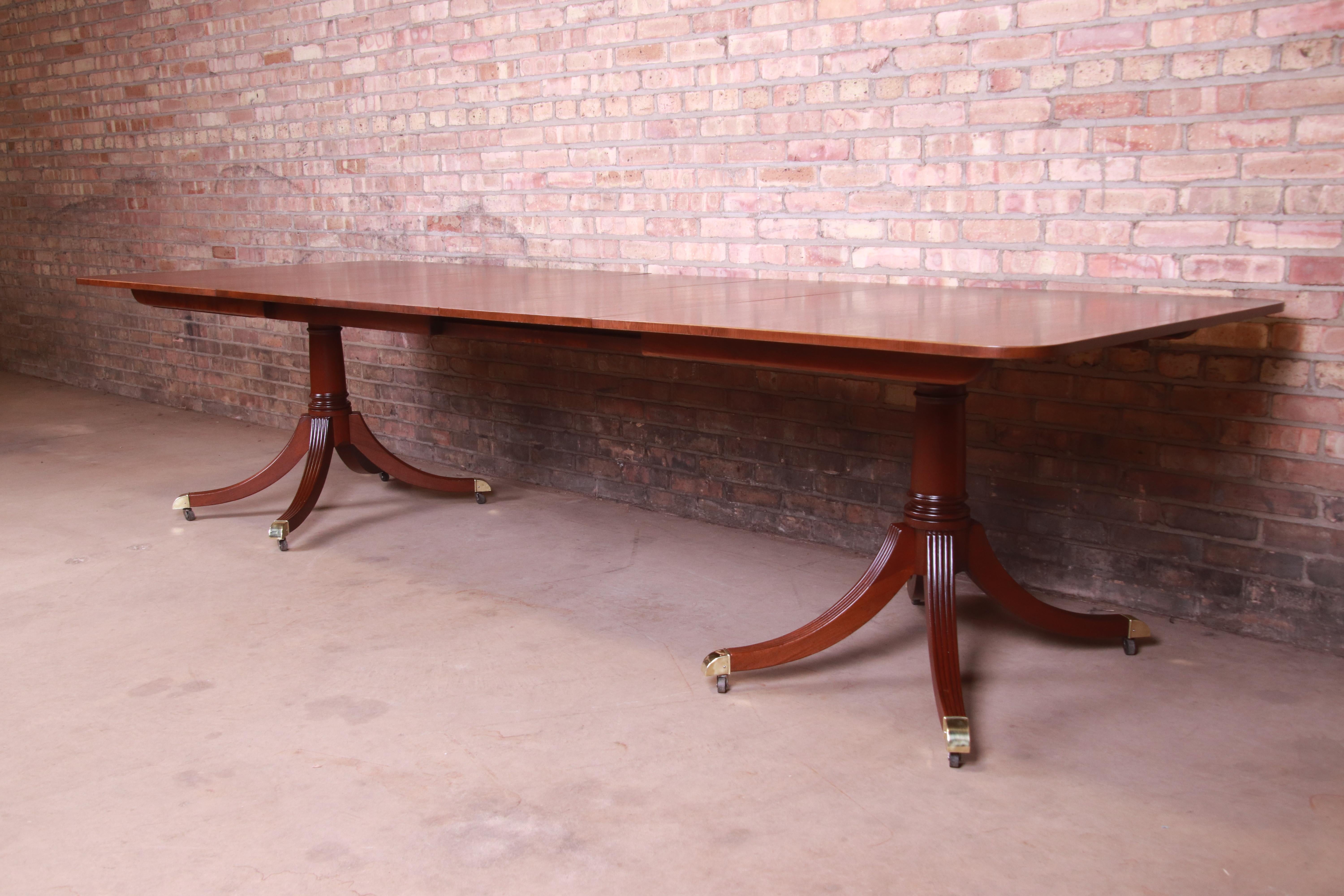 An exceptional Georgian style double pedestal extension dining table

By Baker Furniture

USA, circa 1960s

Book-matched banded mahogany with satinwood string inlay, carved solid mahogany pedestals, and brass-capped feet.

Measures: 68