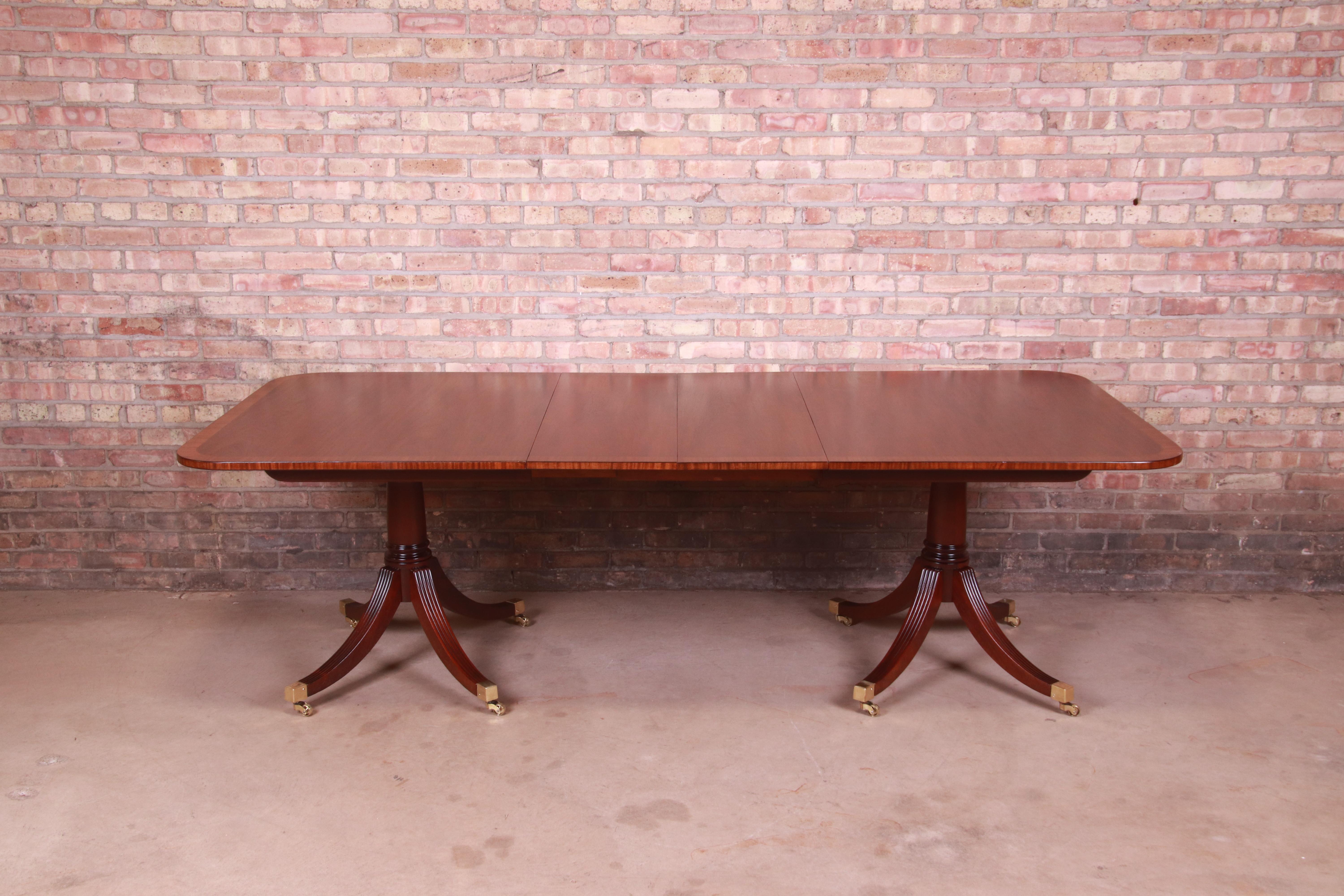 An exceptional Georgian style double pedestal extension dining table

By Baker Furniture

USA, Circa 1940s

Banded mahogany, with carved solid mahogany pedestals, brass-capped feet, and brass casters.

Measures: 68