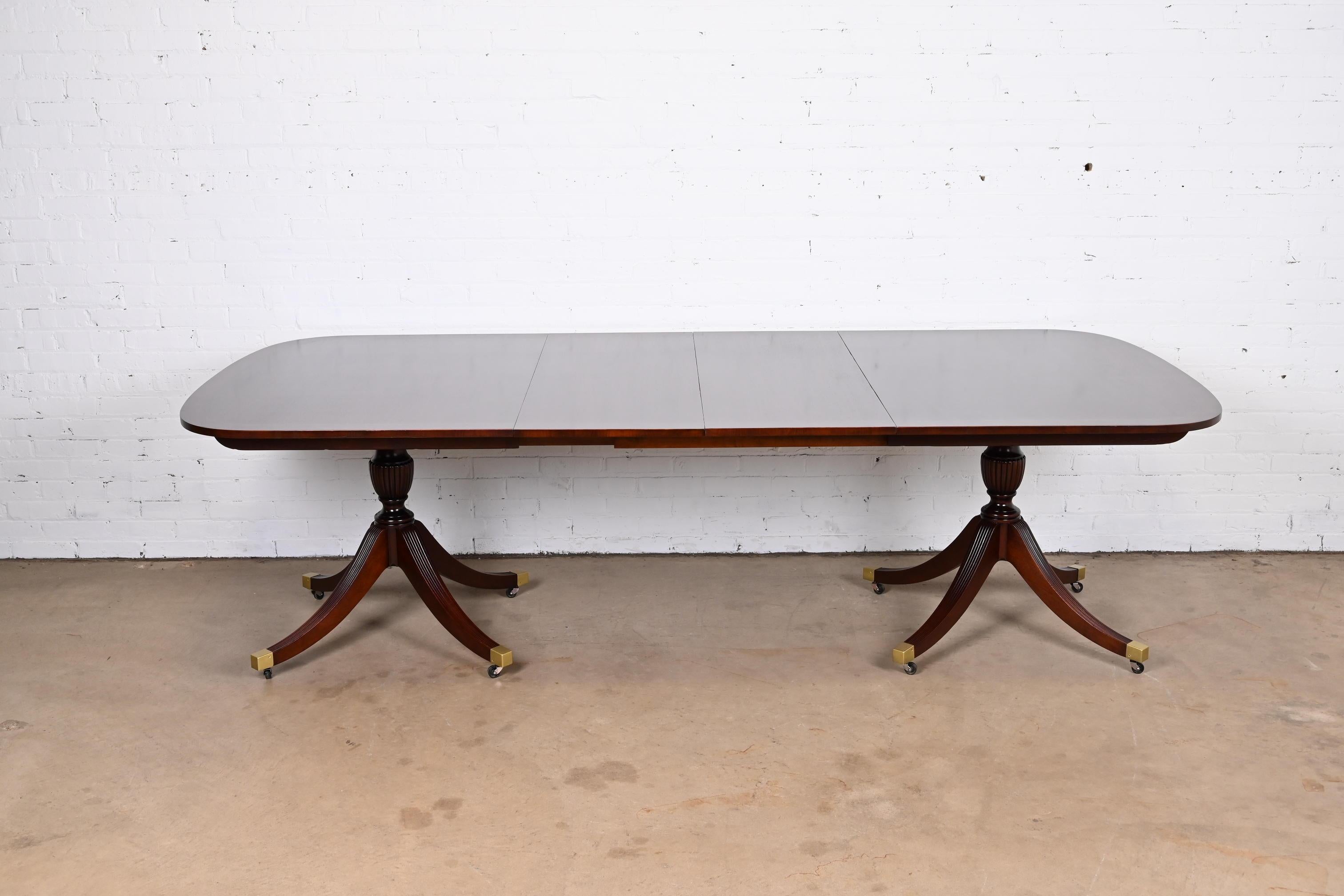 An exceptional Georgian or Regency style double pedestal extension dining table

By Baker Furniture

USA, Circa 1950s

Mahogany, with inlaid satinwood banding, carved solid mahogany pedestals, and brass-capped feet.

Measures: 68