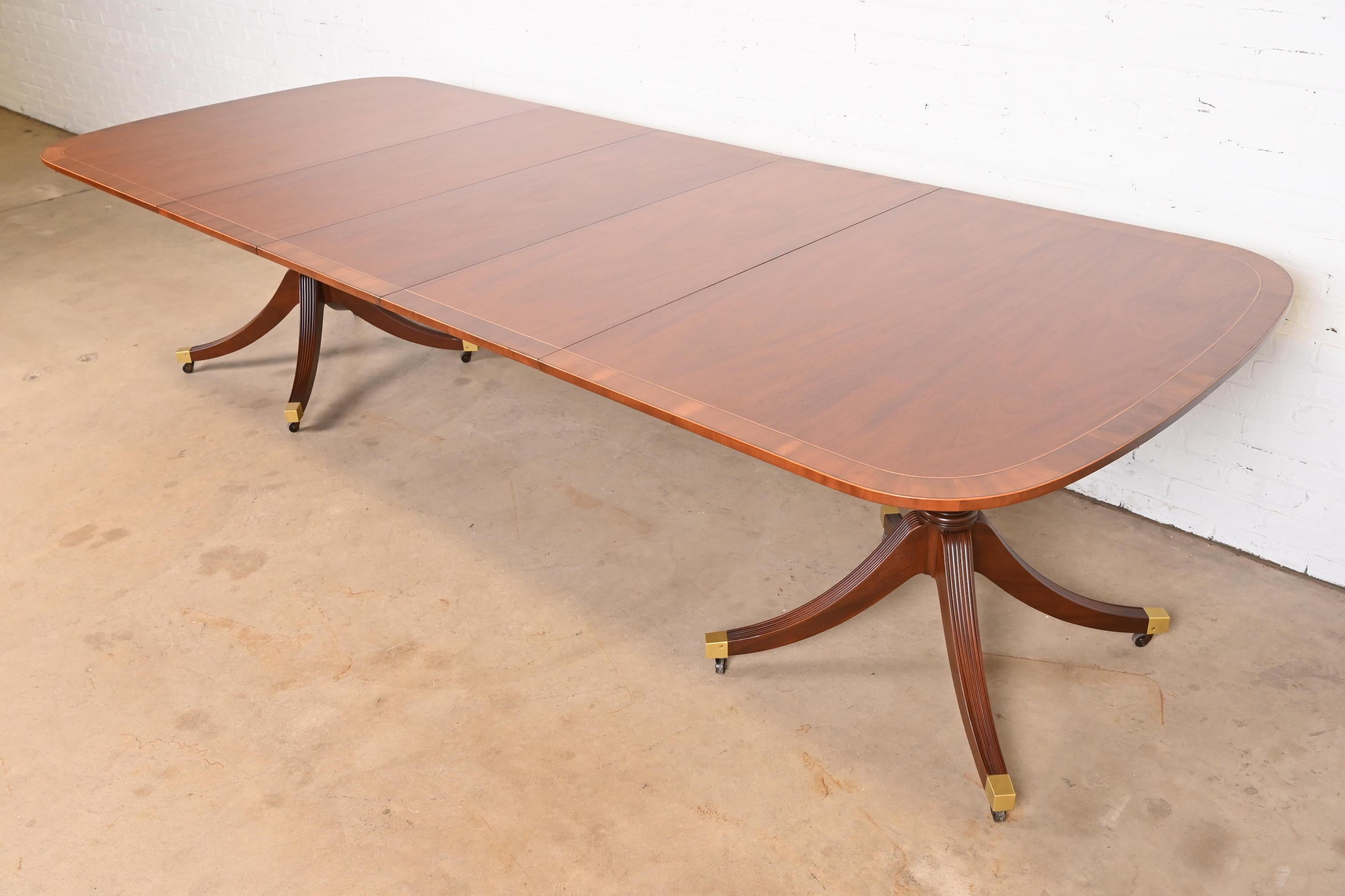 An exceptional Georgian or Regency style double pedestal extension dining table

By Baker Furniture

USA, Circa 1960s

Gorgeous book-matched mahogany, with satinwood string inlay, English yew wood banding, carved solid mahogany pedestals, and brass