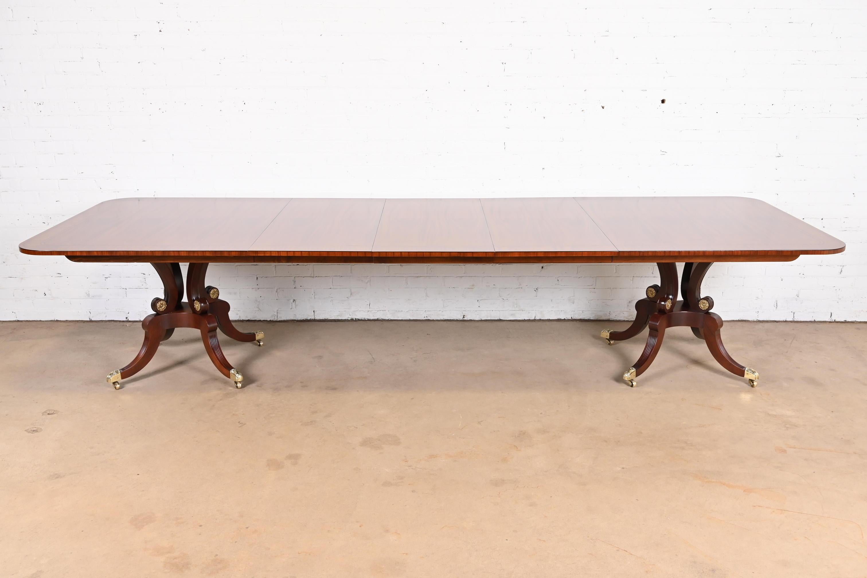 An outstanding Georgian or Regency style double pedestal extension dining table

By Baker Furniture

USA, Circa 1980s

Gorgeous book-matched mahogany, with satinwood banding, carved solid mahogany pedestals, and brass paw feet on brass