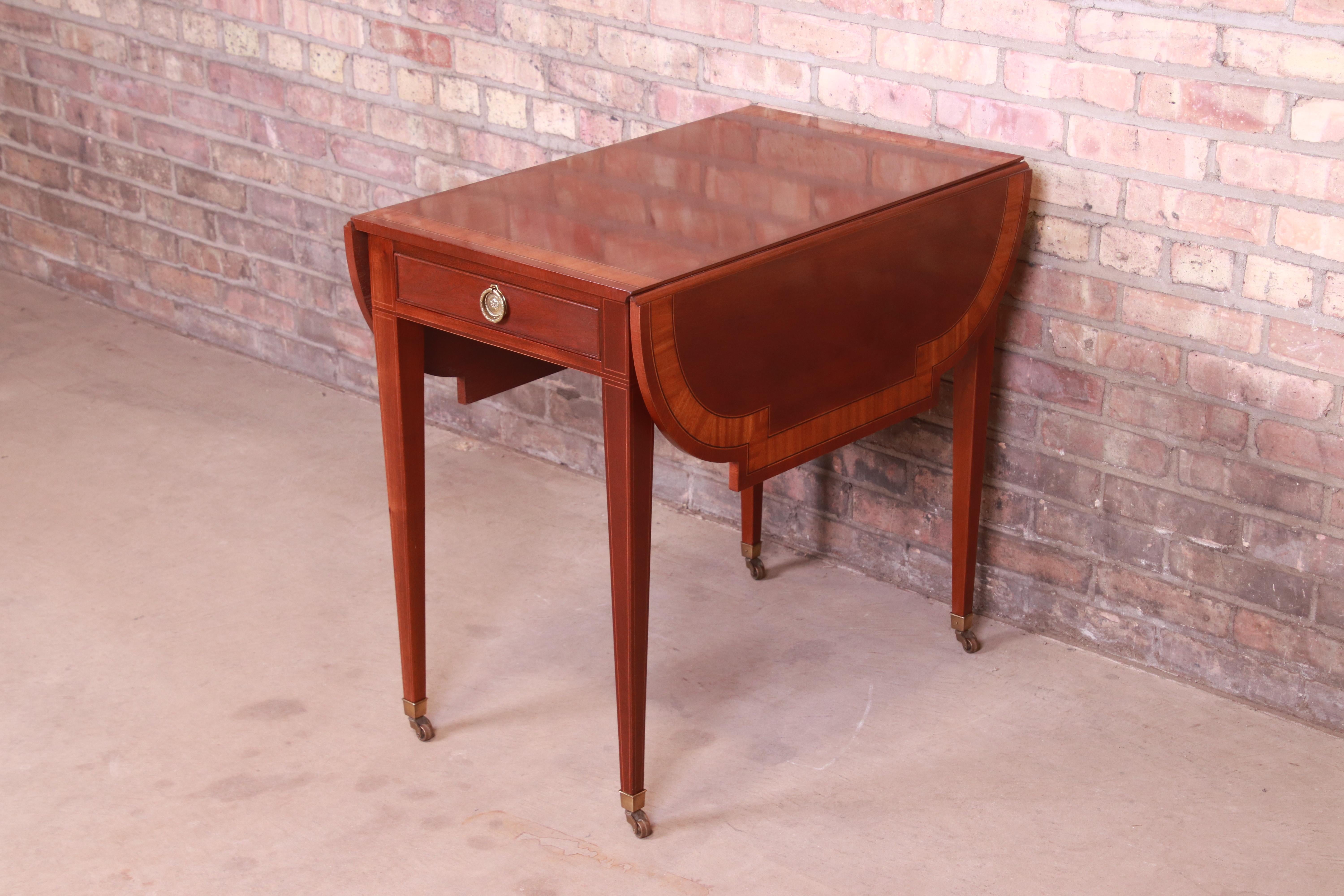 A gorgeous Georgian style Pembroke nightstand or side table

By Baker Furniture,

USA, Circa 1980s

Mahogany, with satinwood banding and original brass hardware.

Measures: 19.25
