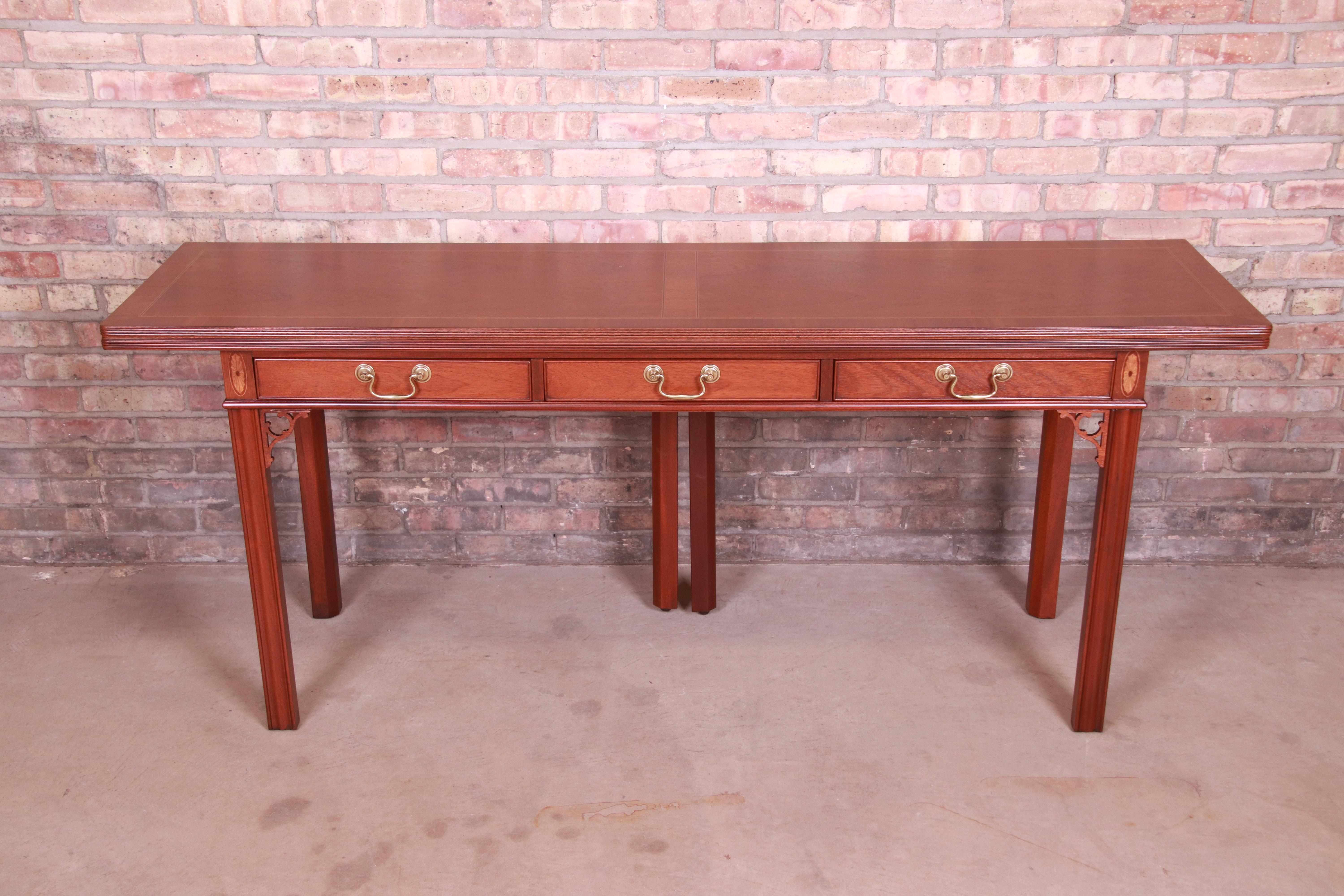 An exceptional Georgian or Chippendale style flip top expanding console, game table, or writing desk

By Baker Furniture

USA, Circa 1980s

Carved mahogany, with inlaid satinwood and original brass hardware.

Measures: 72