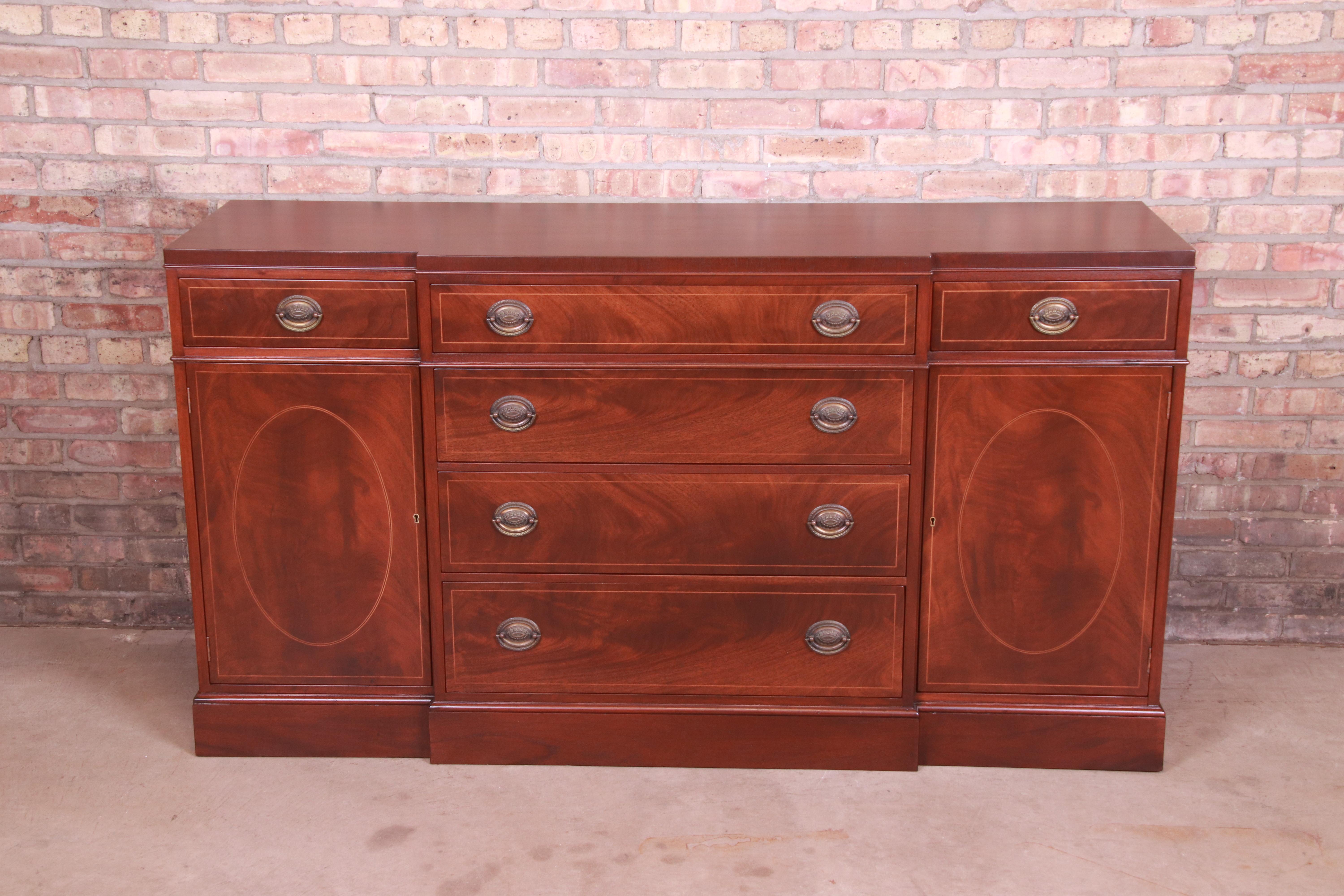 A gorgeous Georgian style sideboard, credenza, or bar cabinet

By Baker Furniture

USA, Circa 1980s

Book-matched mahogany, with satinwood string inlay and original brass hardware.

Measures: 66.25