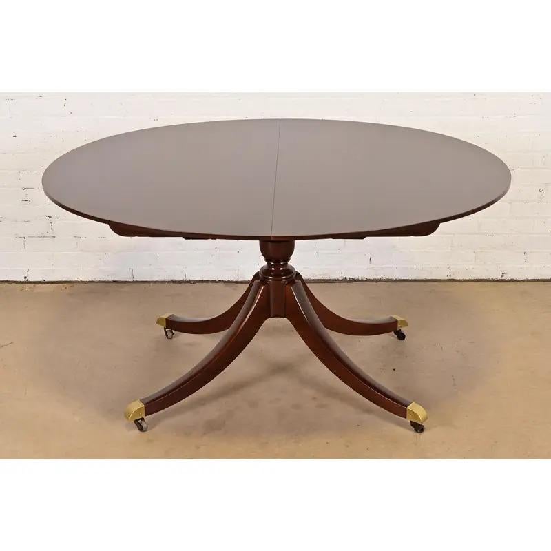 An exceptional Georgian or Regency style pedestal extension dining table 

By Baker Furniture

USA, Circa 1960s

Beautiful book-matched cherry wood, with inlaid ebony string banding, carved pedestals, and brass-capped feet on casters.

Measures: