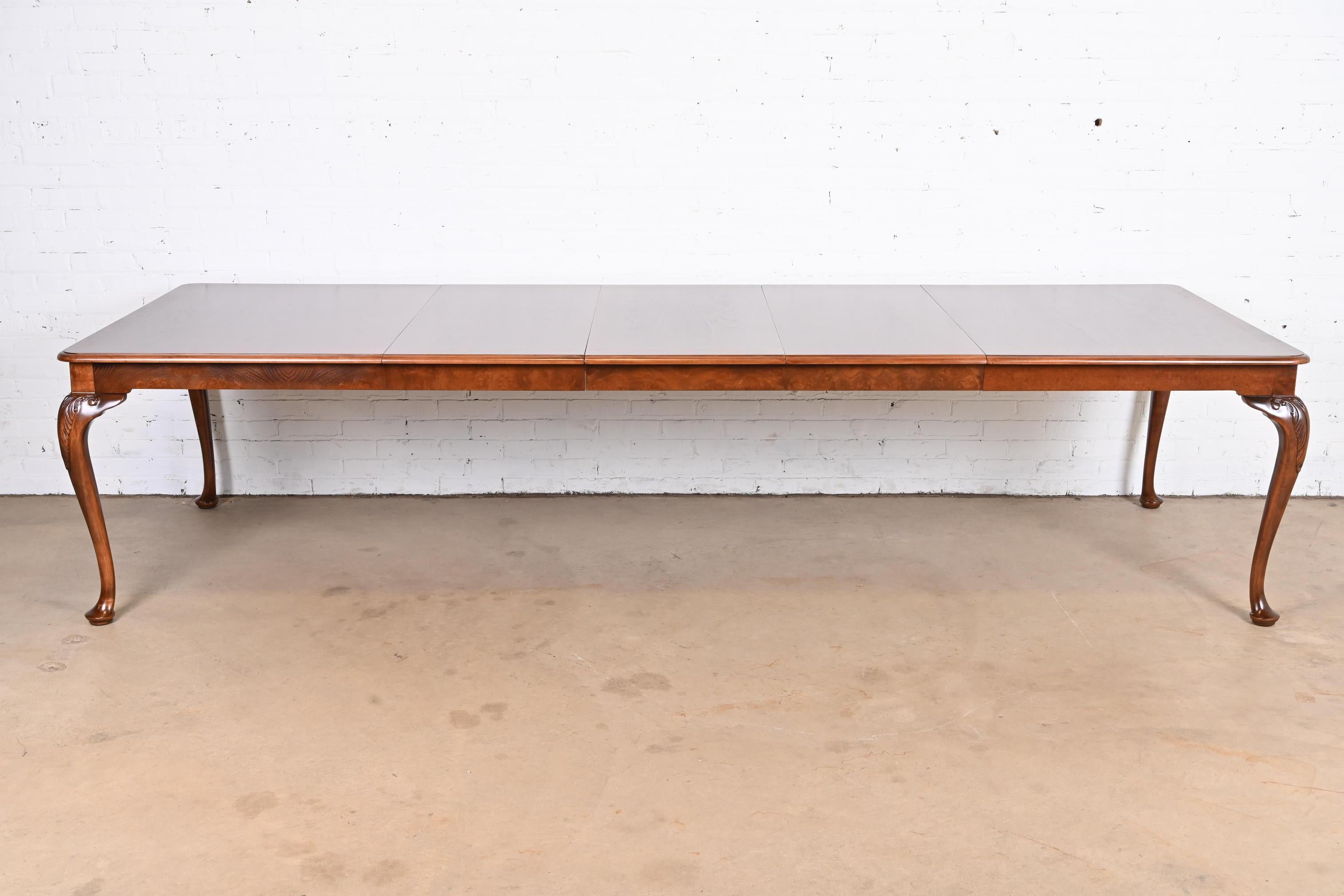 An exceptional Queen Anne, Georgian, or Chippendale style extension dining table

By Baker Furniture

USA, circa 1980s

Book-matched banded walnut top, with satinwood inlay, burled walnut apron, and solid walnut cabriole legs with carved